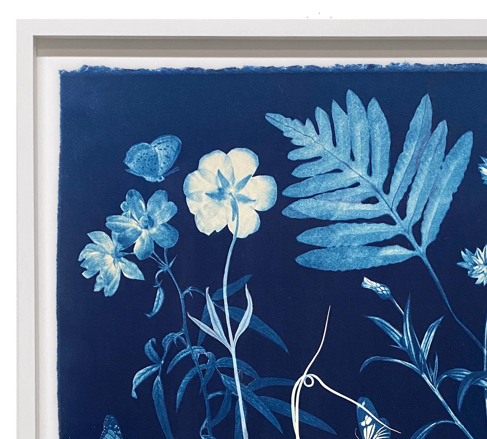 In this vertical work in watercolor, gouache, and cyanotype on cotton Arches paper, leaves and meticulously detailed flowers, including roses and snowdrops are depicted in white and shades of pale blue against a deep, indigo blue background, while