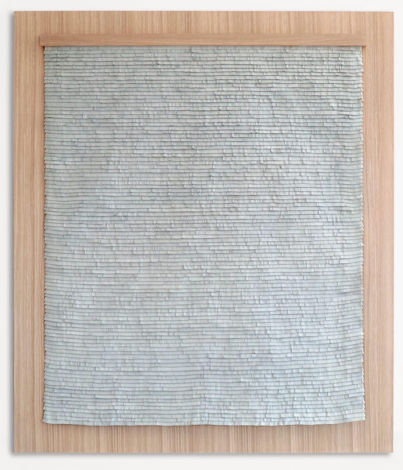 Obra de arte tejida en cuero con flecos grises sobre madera