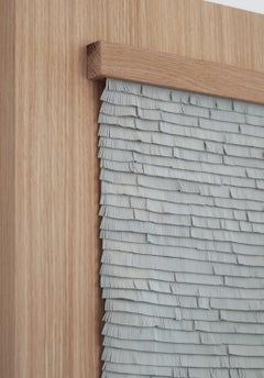 Leather woven artwork with grey fringes on wood