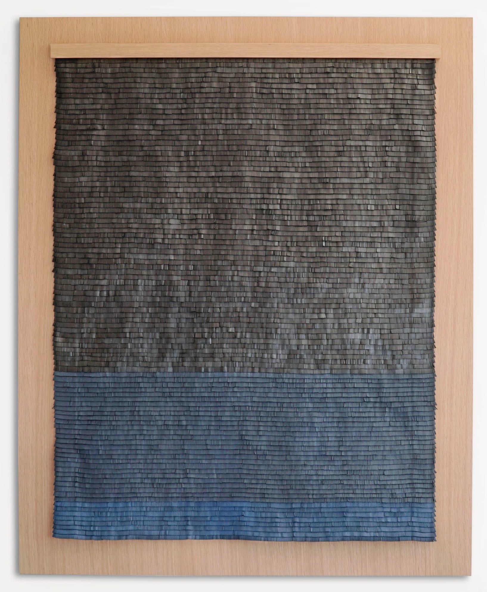 Obra de arte tejida en cuero con degradado de color azul y negro sobre madera