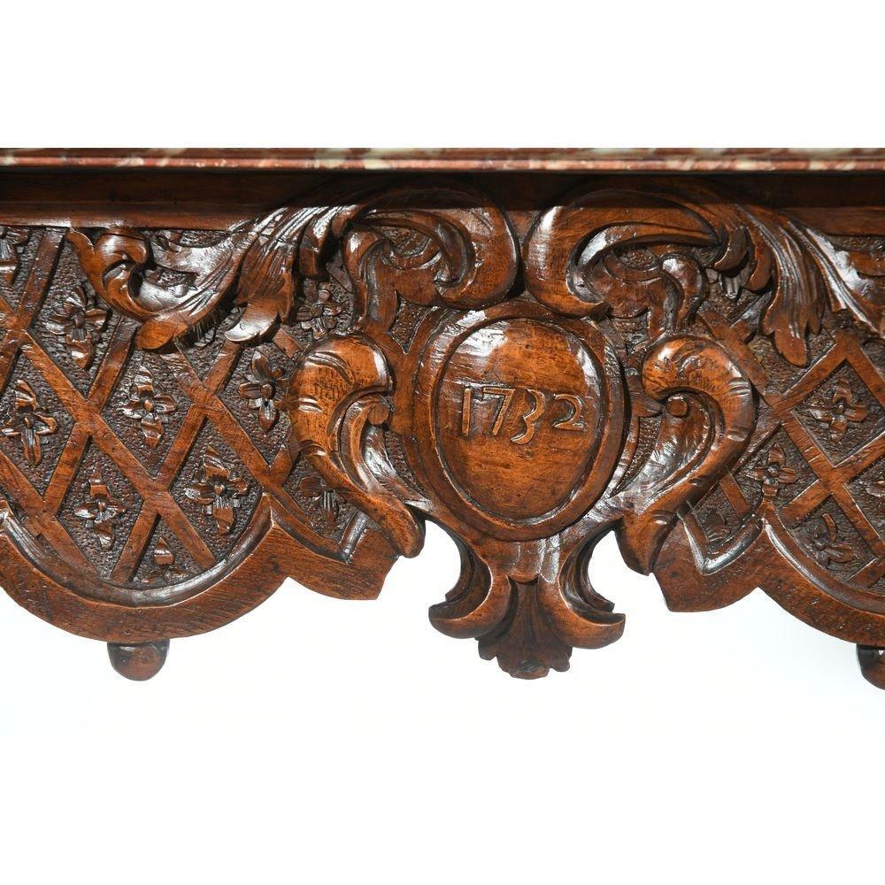 TABLE A GIBIER DE MILIEU RÉGENCE en bois naturel à jolie patine. Elle est à motifs sur la ceinture de quadrillages et d'un médaillon central avec la date 1732. Sie ruht auf geschliffenen, skulpturierten Füßen, die mit Säbeln abschließen. Dessus de