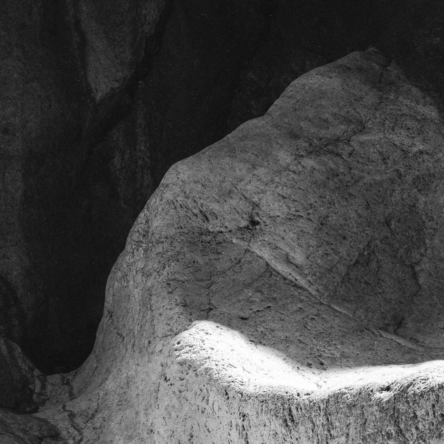 Earth VI - Photographie en noir et blanc, Grotte, Roches, Paysage naturel, Lumière - Noir Landscape Photograph par John Stathatos