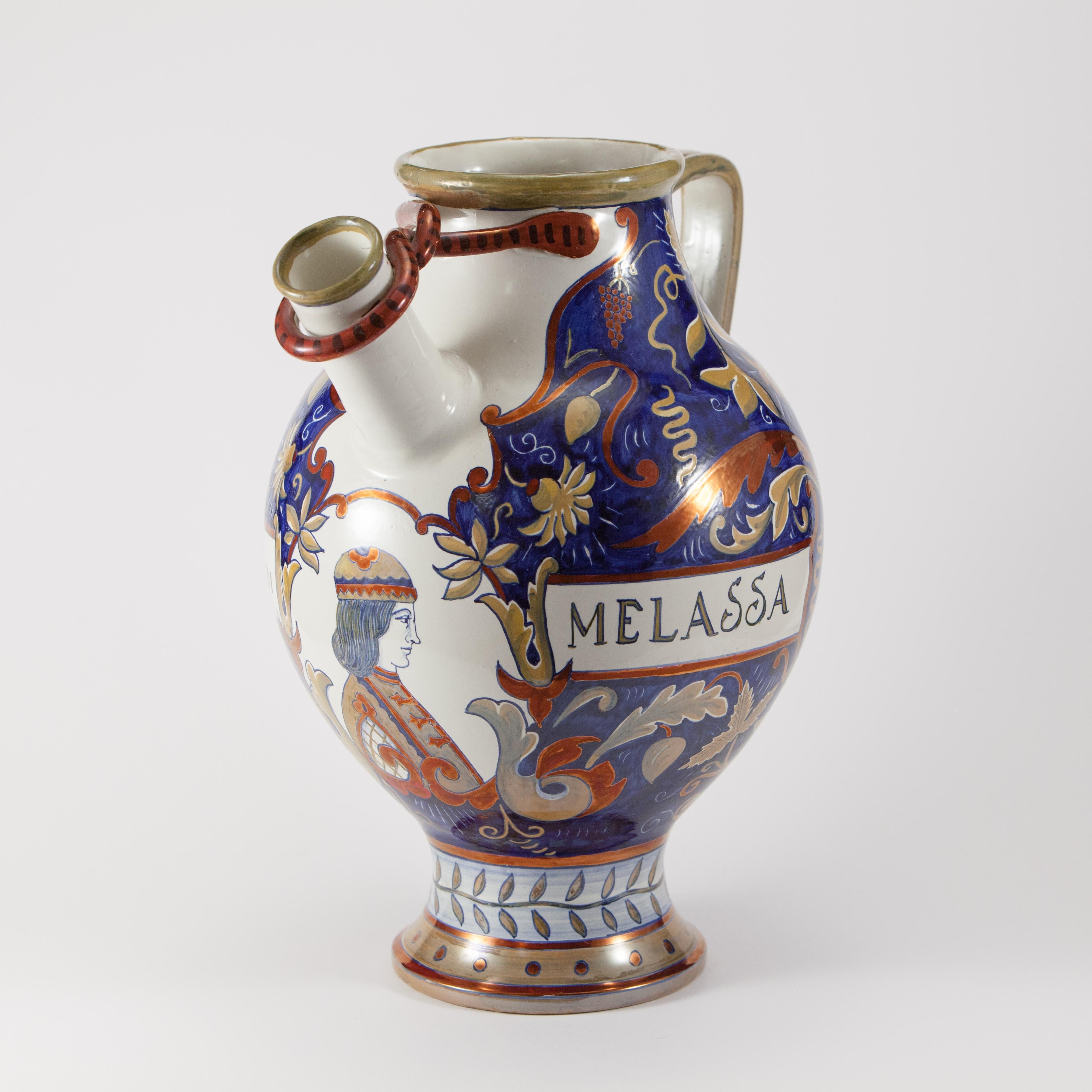 Majolica pourer with handle, decorated with metallic luster in the style of Renaissance majolica in shades of blue, yellow, red.
The vase houses a medallion on the front with a half-bust and the inscription 