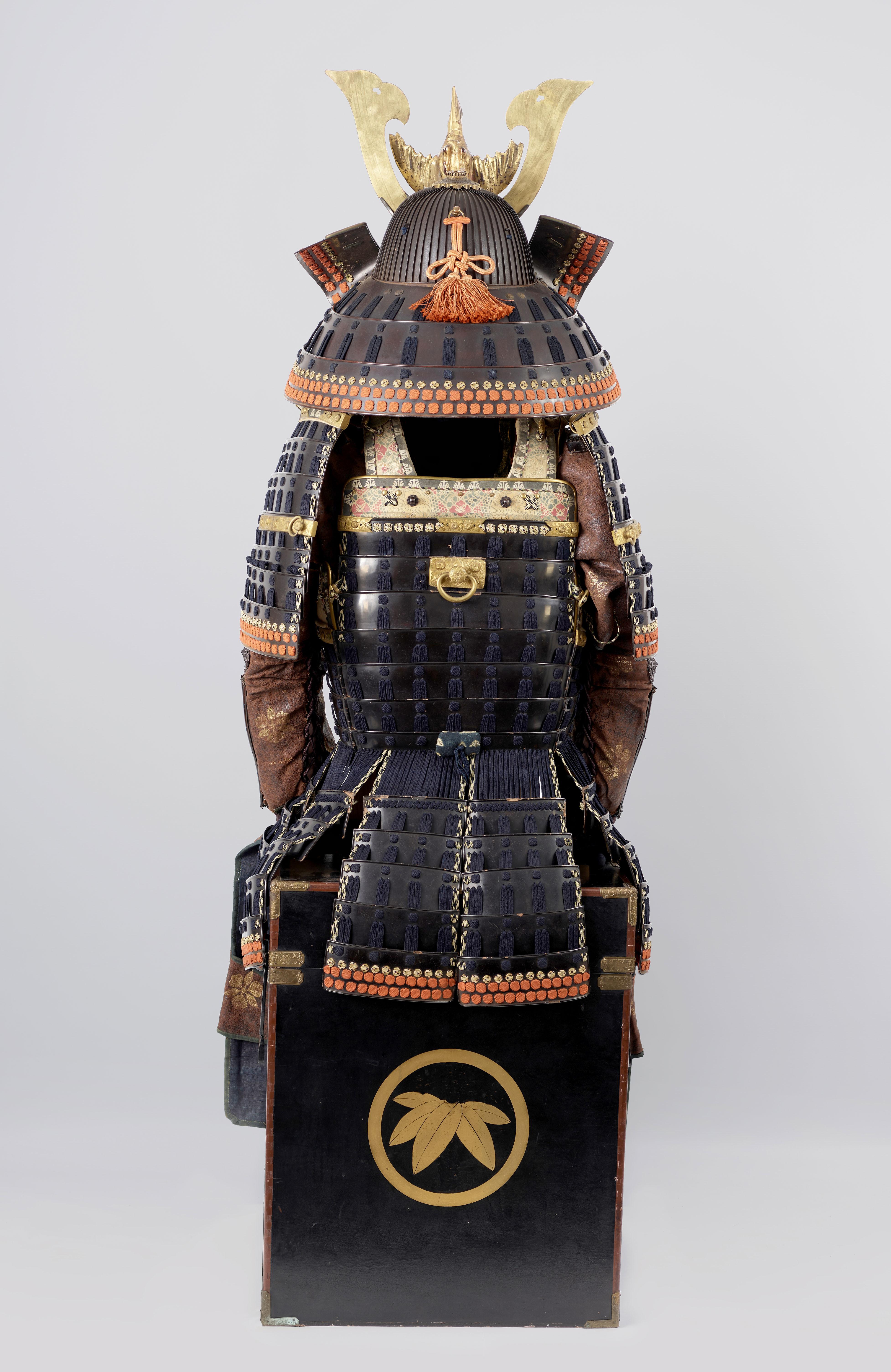 A 52-plate iron helmet, black lacquered and signed by Neo Masanobu of the Neo-School. It features a large, black lacquered, three-lame manju-jikoro (neck guard) laced in silk in the sugake style. The interior has a leather ukebari (liner) with a