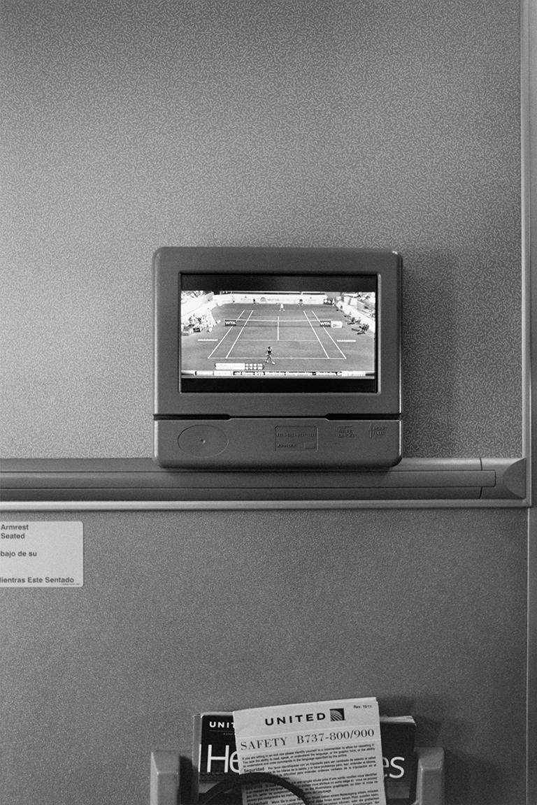 Stephan Würth Black and White Photograph - Watching Tennis on United Airlines flight