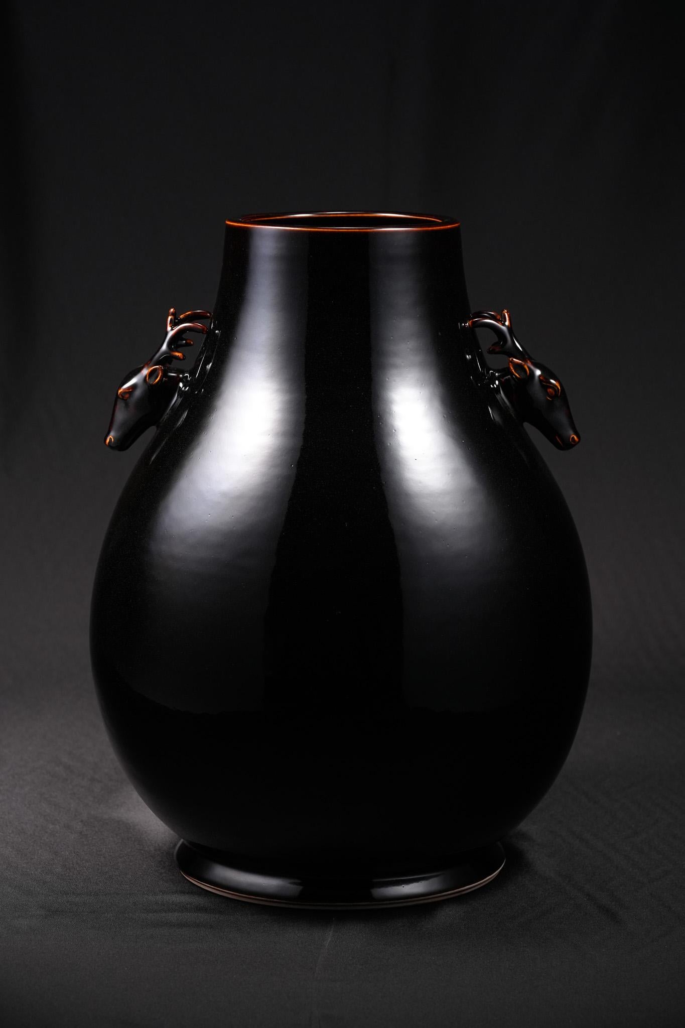 Shi Jie Weng’s Black-Gold Deer-Head Vase has a solid and stately form, with a rounded, full body and lifelike deer heads on either side serving as handles. The antlers curve with strength and elegance, their fine detail showing the artist’s