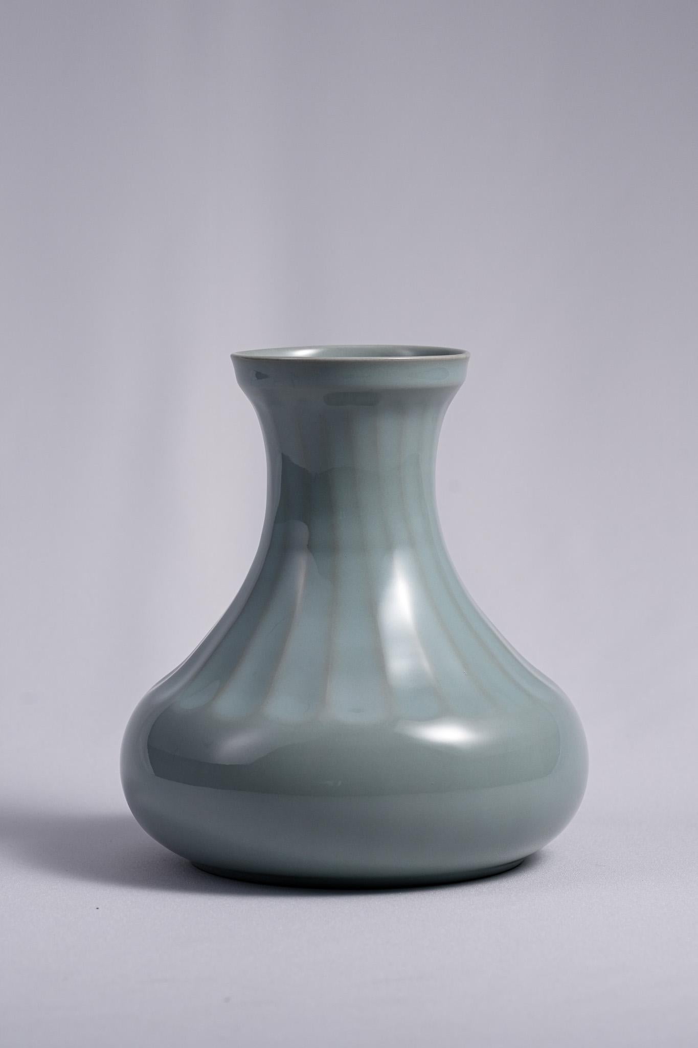 This Celadon Vase by Shinobu Kawase exemplifies the serene elegance of celadon. The vessel features simple, graceful curves and a balanced melon-ribbed form that conveys quiet strength and stability. Covered in a soft bluish-green glaze with a