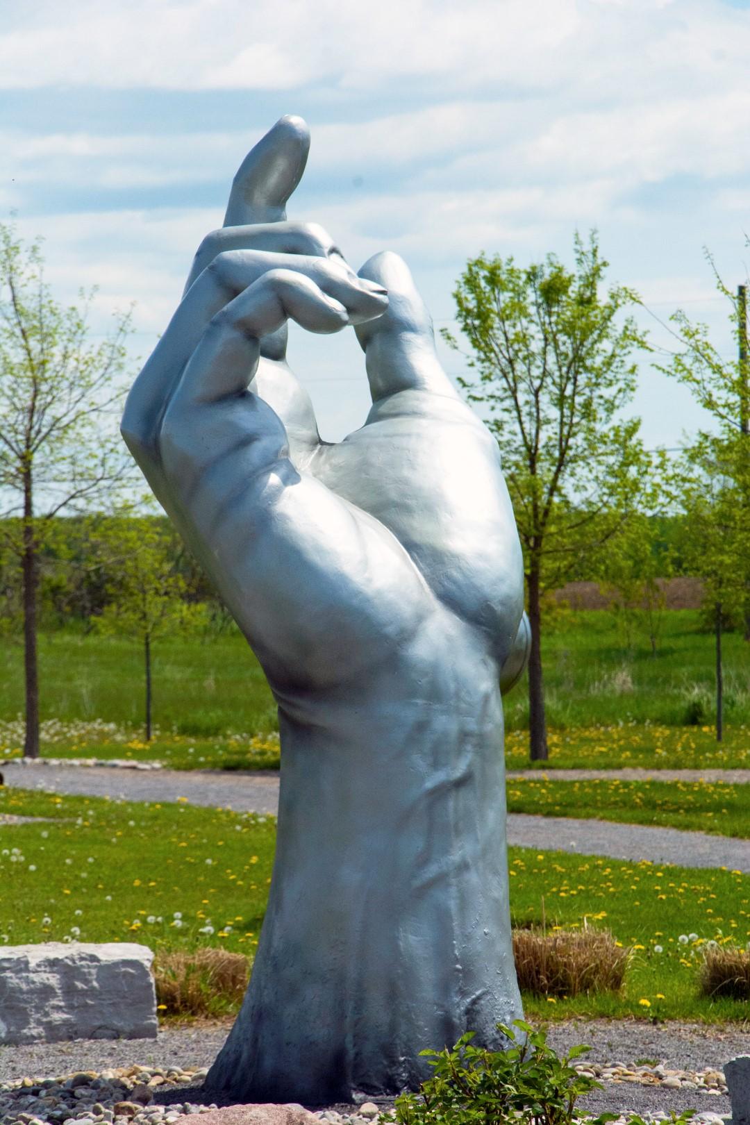 Créée par l'artiste canadien David Sheridan, cette sculpture extérieure en fibre de verre est une intersection unique de la sculpture figurative pop et classique. L'index de la main massive pointe vers le ciel, mais de manière plus ouverte que le