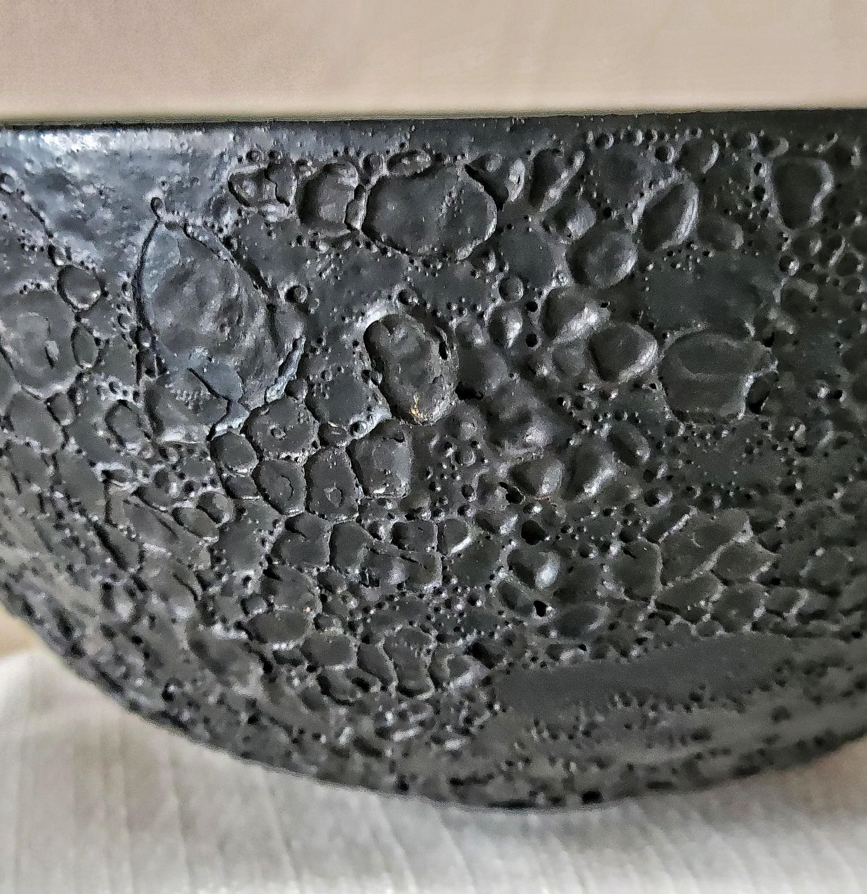 Ce magnifique bol Black Lava de Gertrud et Otto Natzler présente l'une de leurs formulations de glaçure volcanique les plus spectaculaires et les plus recherchées. La surface est recouverte d'une texture dense et cratérisée de 