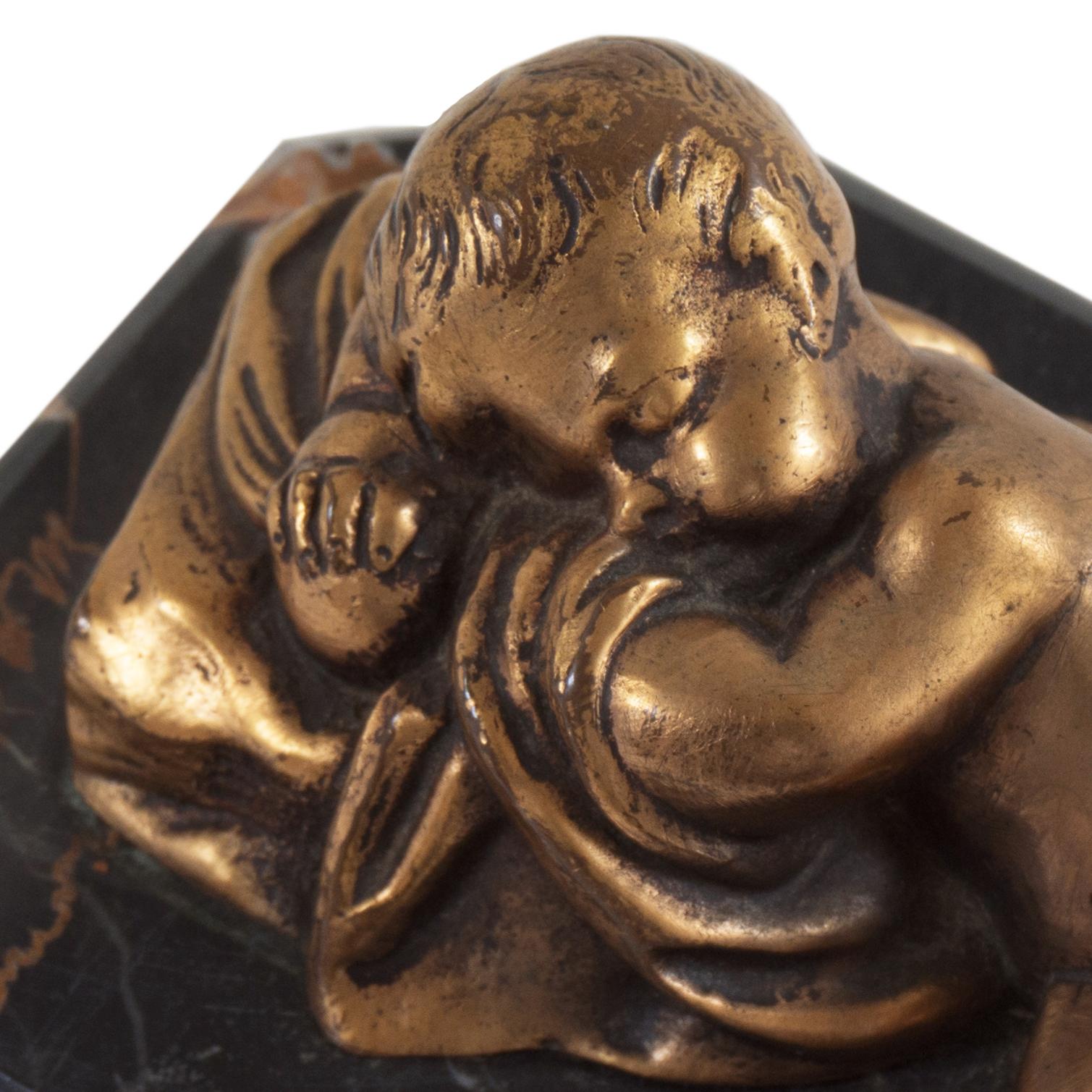 A finely modeled, gilt bronze figural statue of a sleeping cherub shown reclining and asleep with his head resting on a folded blanket. Mounted on the original, chamfered Portoro marble base. French School circa 1900, indistinctly signed in casting.