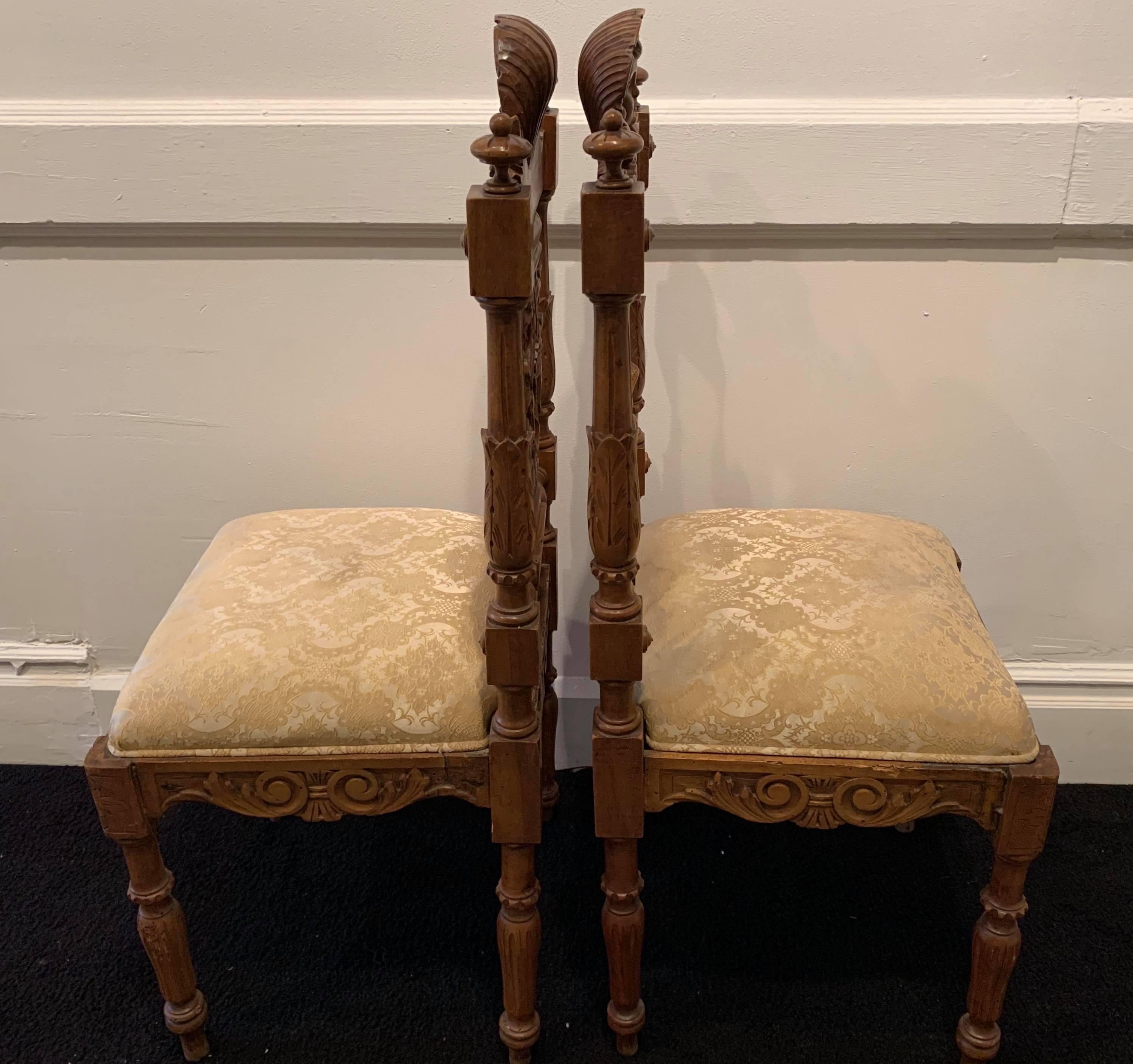 These 19th Century hand-carved hall chairs from Mexico are reminiscent of a Renaissance style in the design of the faces of the angels and ornamentation. This native wood is walnut colored with a stain that gives the chairs a caramel glow. The