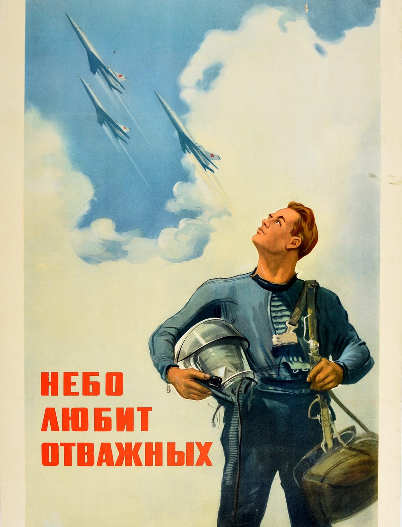 Original vintage Soviet propaganda poster - The Sky Loves The Brave / Небо любит отважных - featuring a pilot in uniform holding a helmet and looking up at fighter jet planes marked with red Soviet stars flying through the clouds above, the bold red