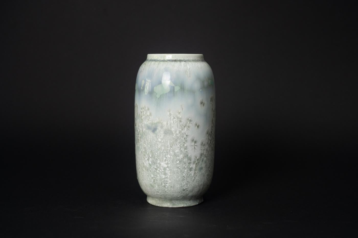Ice Storm Vase by Valdemar Engelhardt. The tall, cylindrical body rests on a slightly narrowed foot which is harmonious in proportion to the mouth; with sea foam green and periwinkle blue glaze set against a white ground, the vessel is a study in