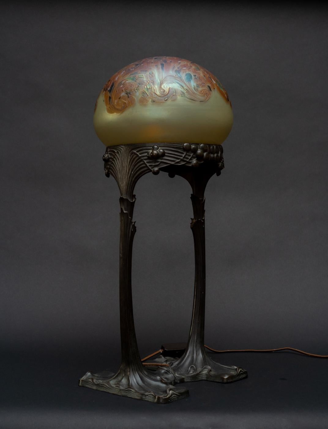 ART NOUVEAU BALLOON GLASS TABLE LAMP, by Gustav Gurschner and Johann Loetz Witwe, c. 1904, the glass dome in a frosted yellow iridescent ground is crowned by orange abstract swirls accented by dabs of aubergine and green; it rests on a chocolate