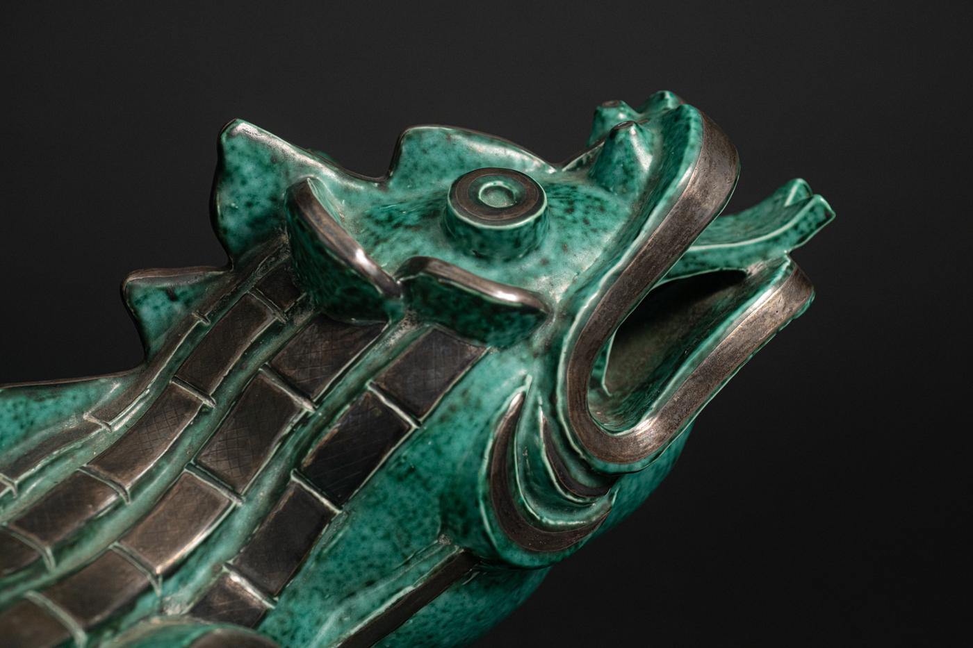 ARGENTA DRAGON, by Wilhelm Kåge (Swedish, 1889-1960), aqua green-glazed stoneware with sterling silver accents, mounted on a custom molded wood base, c. 1930, most likely an exhibition piece. The striking mottled aqua green glaze is an early example