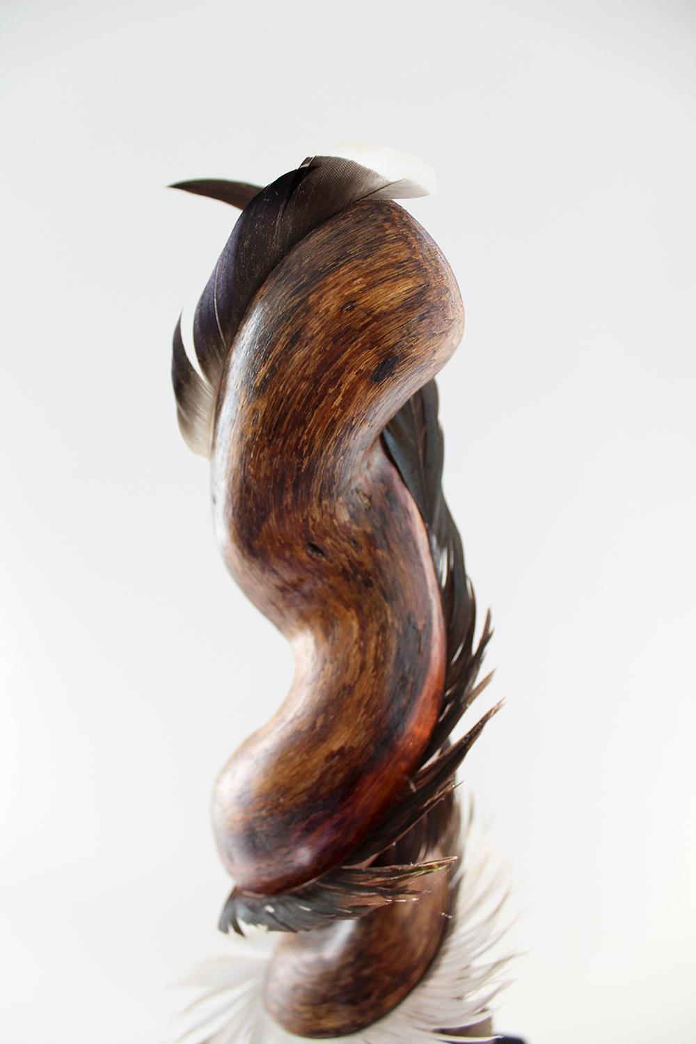 Miller Opie’s “Swishing Larkspur” is a gestural 27 x 6 x 6 inch White Oak wood sculpture with found feather details embedded into the wooden grain. It is the fifth piece in her 8 piece 