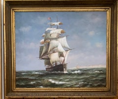 19th century style American tea clipper-sailboat at sea with a landscape beyond.