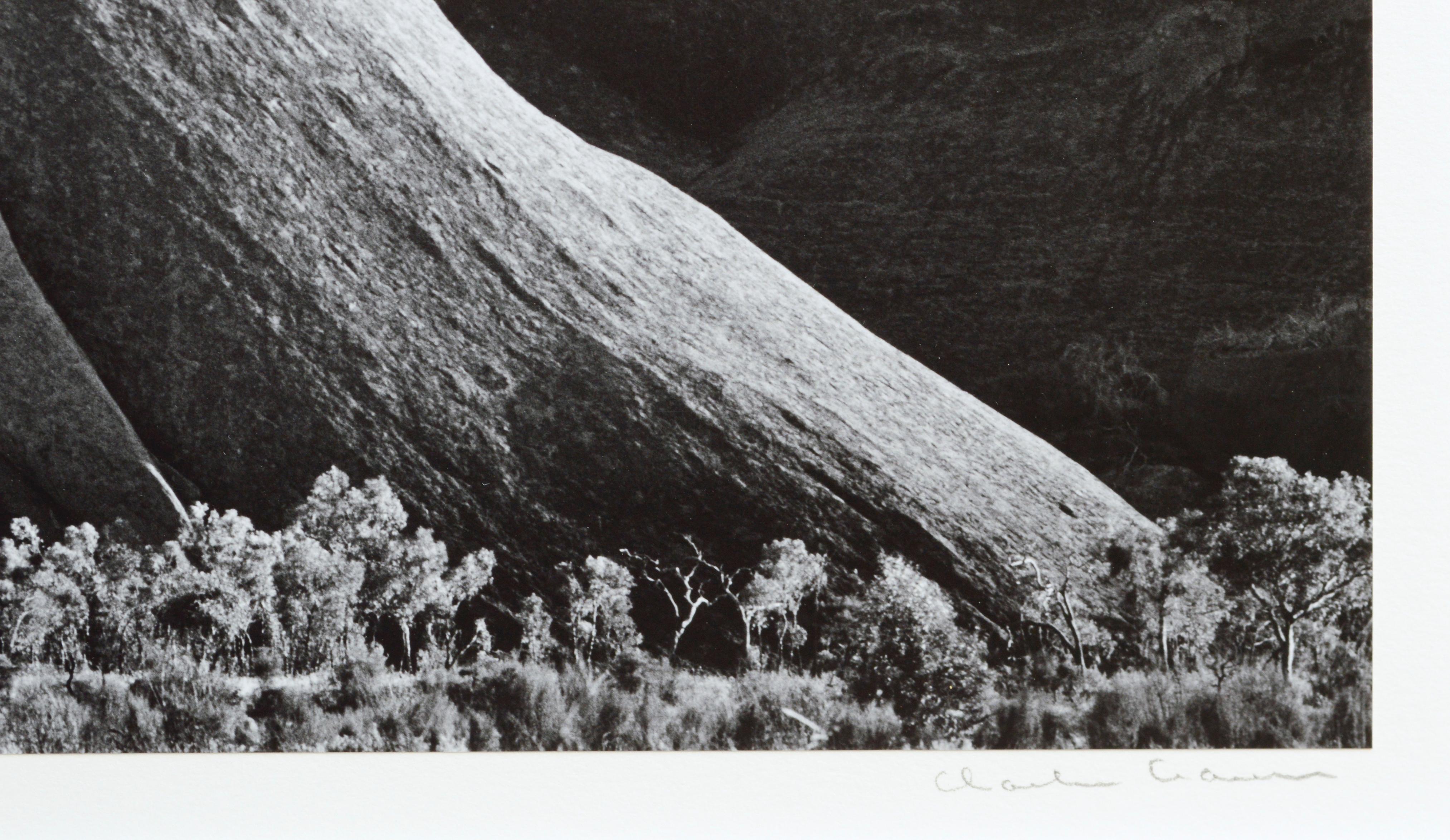 Betrachten Sie die atemberaubende Schönheit der Natur auf dieser handsignierten Schwarz-Weiß-Landschaftsfotografie des wunderschönen Ayers Rock in Australien. Charles Cramer (Amerikaner, geb. 1950) zeigt die elegante Krümmung der dramatischen Klippe
