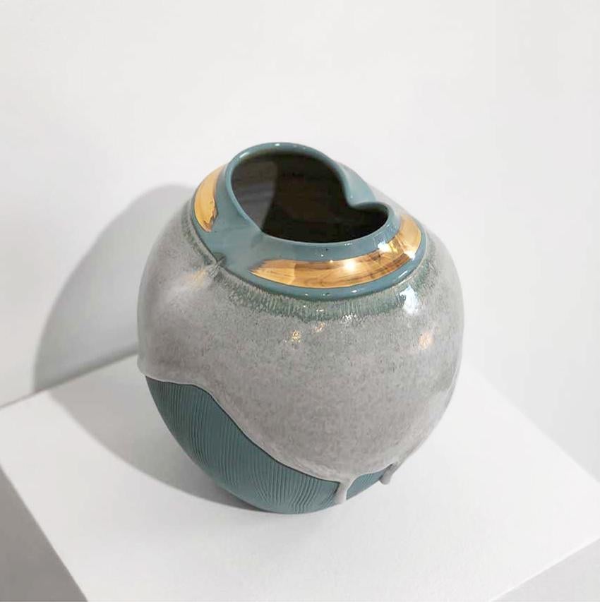 This small ceramic vessel by Connecticut-based ceramicist, Jon Puzzuoli, is made with turquoise porcelain, and has an almost translucent white glaze that is dripped down the top half of the piece. Individual drips move further down the bottom half.