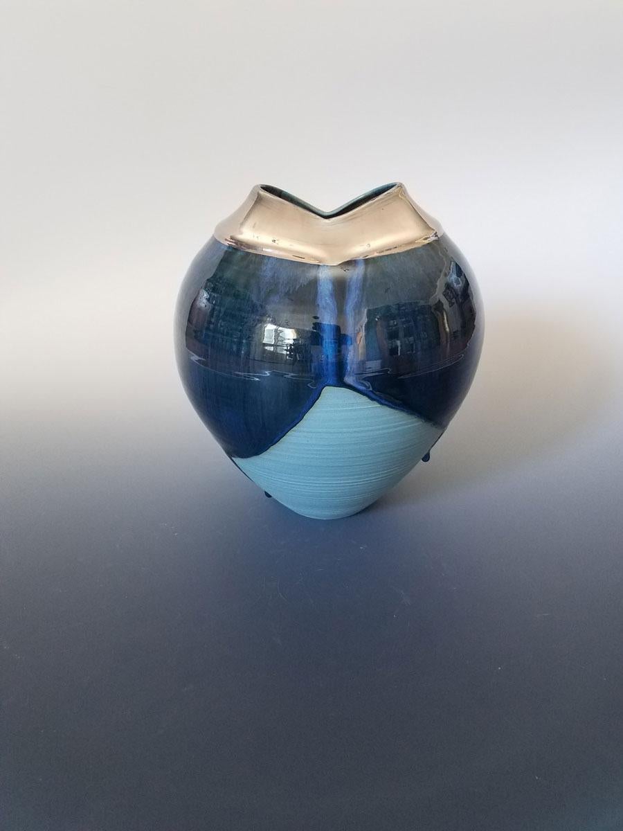 This small, modern vessel by Connecticut-based ceramicist, Jon Puzzuoli, is made with turquoise porcelain. The base of the vessel is made with textured turquoise porcelain. A deep, midnight-blue glaze is intentionally unevenly dripped down the top