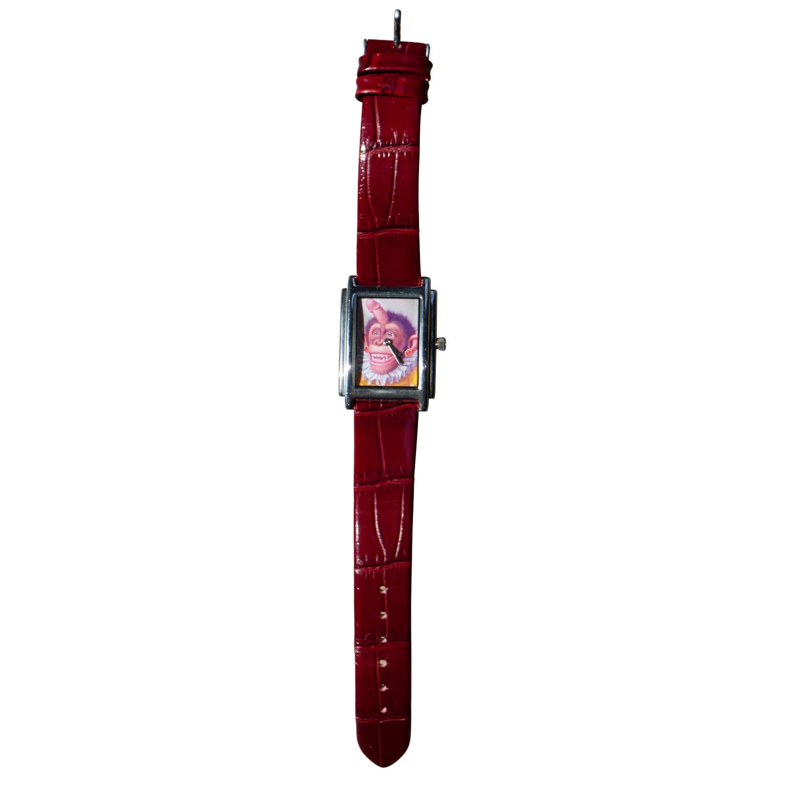 A modern watch by Donald Roller Wilson. The watch features a red patent leather and a dial that features a monkey with male genitalia on its head. The watch has silver metal accents and shows only very minimal wear. Unsigned but it includes a