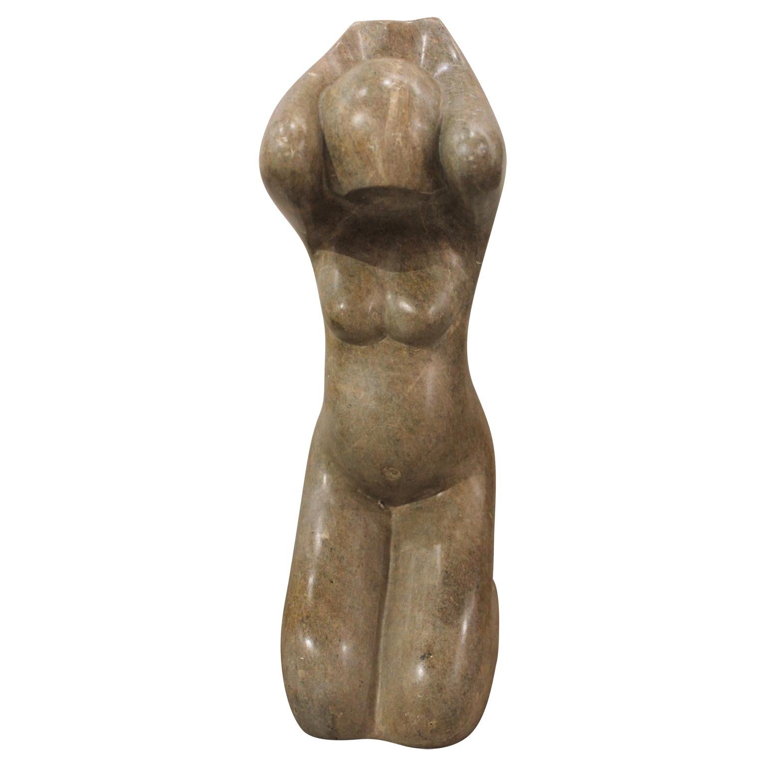 Tan colored stone sculpture of a female figure with hands covering the sides of her head. The sculpture is signed by the artist and dated. Milton Goldin is known for producing abstract figurative works of women in movement.