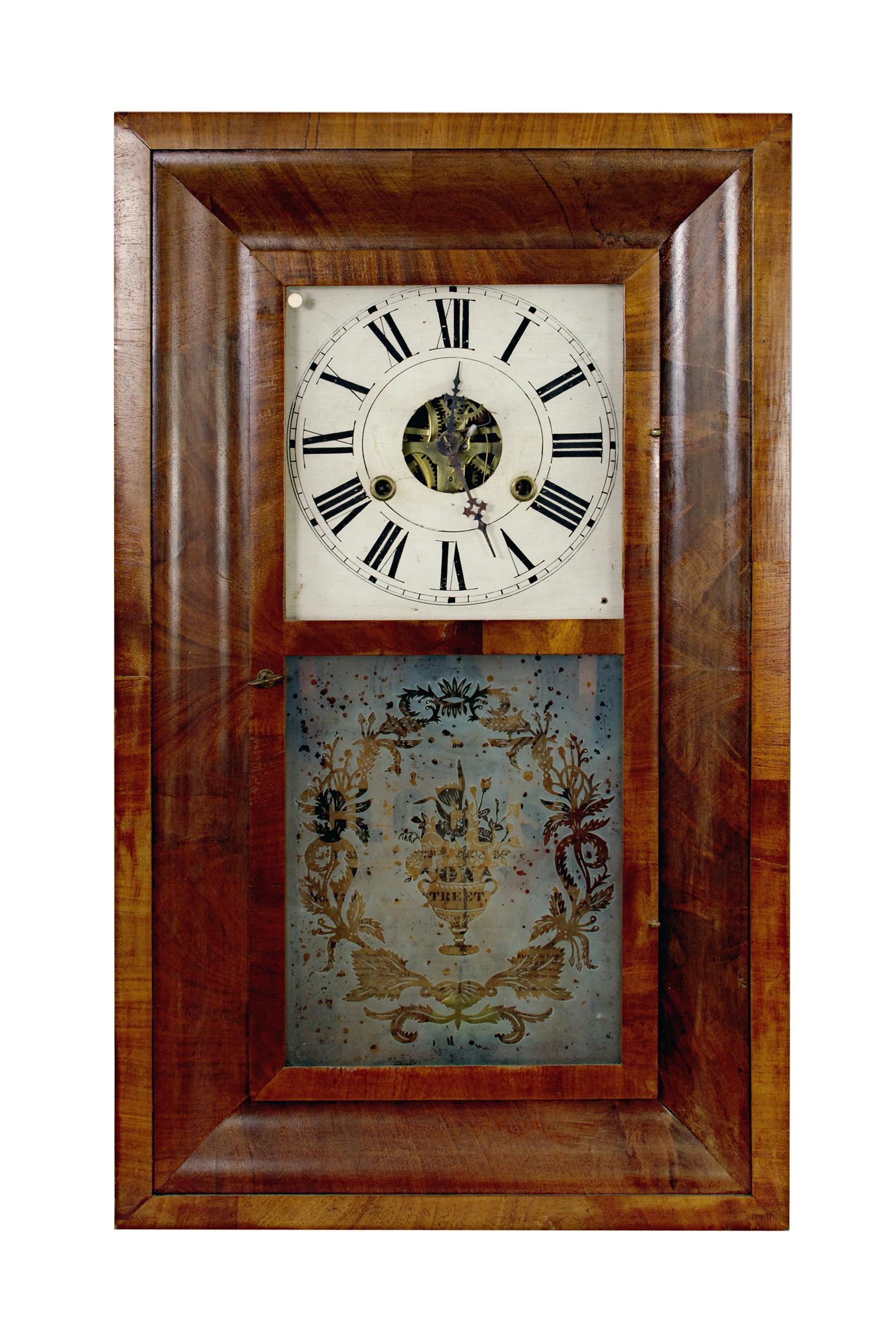 Cette horloge de 30 heures a été conçue par un designer américain nommé W.S. Conan. Il présente un magnifique bois foncé et un verre gravé avec un motif floral. 

26" x 15 1/4" x 4 1/4" 
