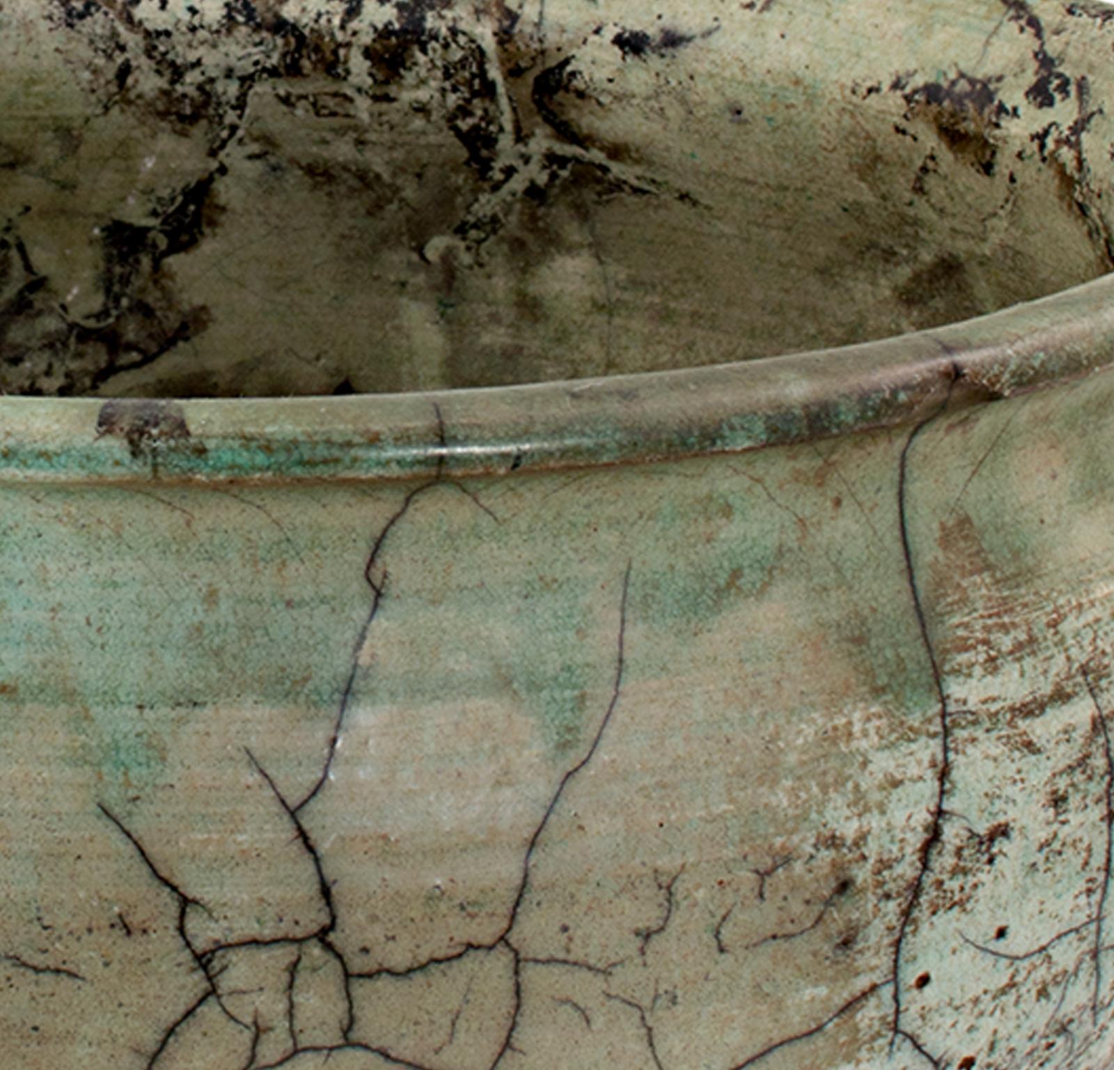 This raku ceramic bowl was created by Ken Kapp. It features earth-colored glaze in green and brown and a cracked petina. 

4