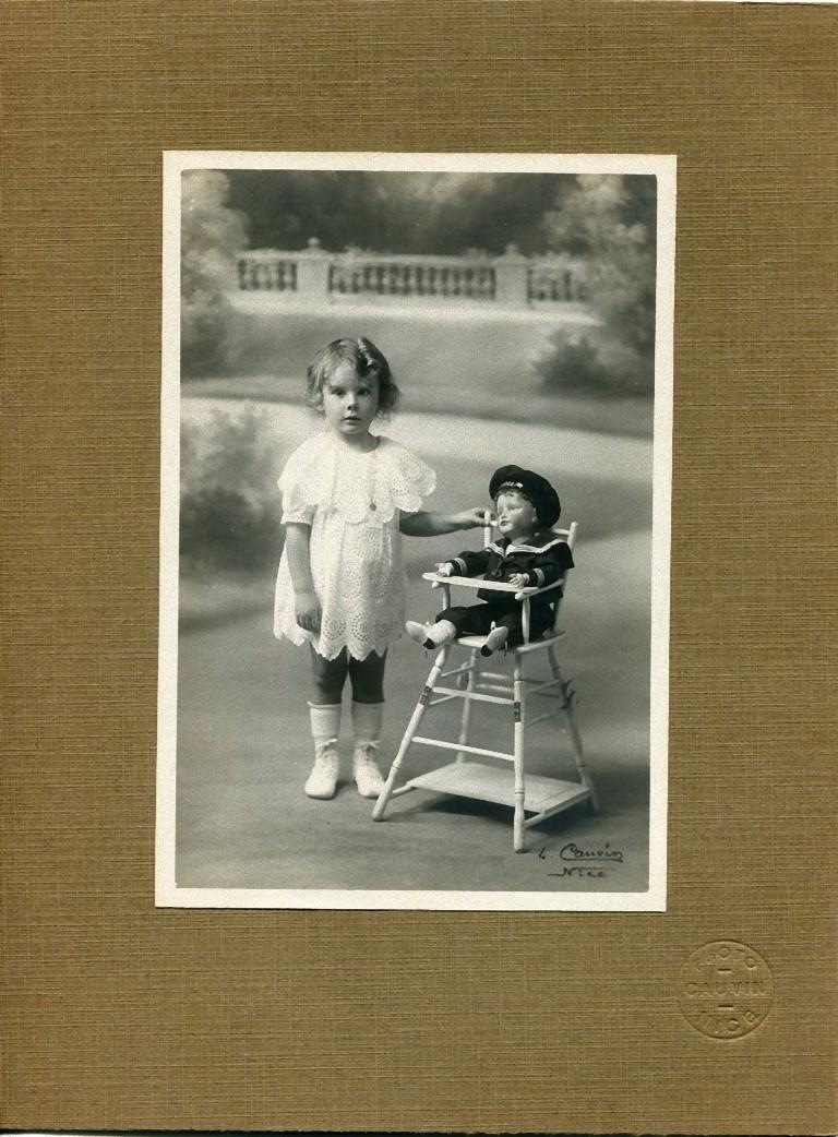 Foto de época de una niña con su muñeca marinera, tomada por Studio Cauvin en Niza, Francia. Perfecto estado, incluye su propia funda con el sello seco del estudio fotográfico.