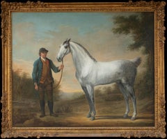 Un Stallion gris tenu par son palefrenier dans un paysage classique