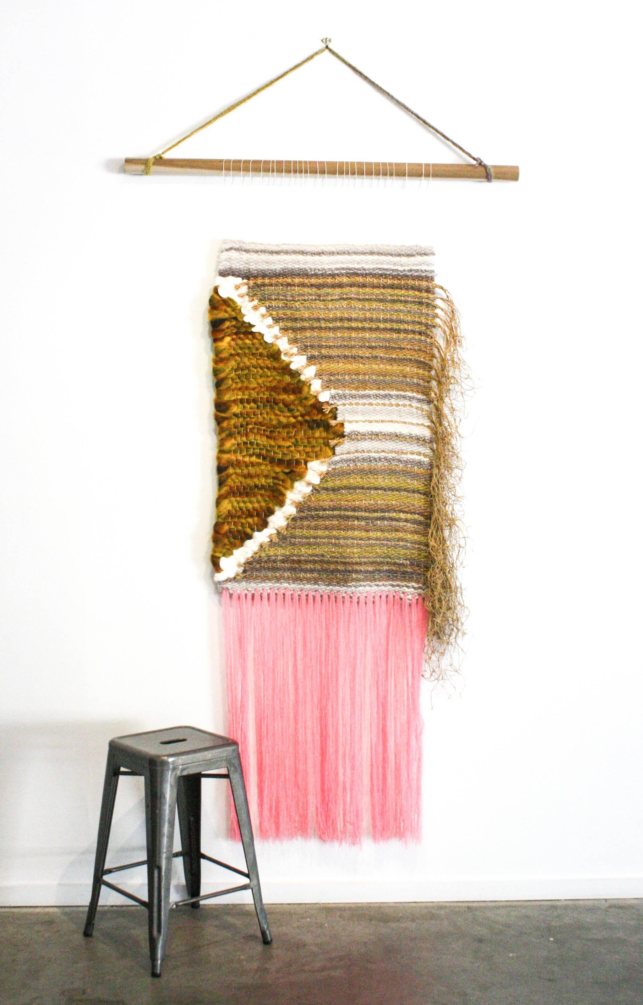 This woven sculptural wall hanging is made using green, brown, white, orange, and pink.

Pam Marlene Taylor is a fiber artist living and working in Nashville, Tennessee. She is a graduate from Tusculum University where she double majored in Studio