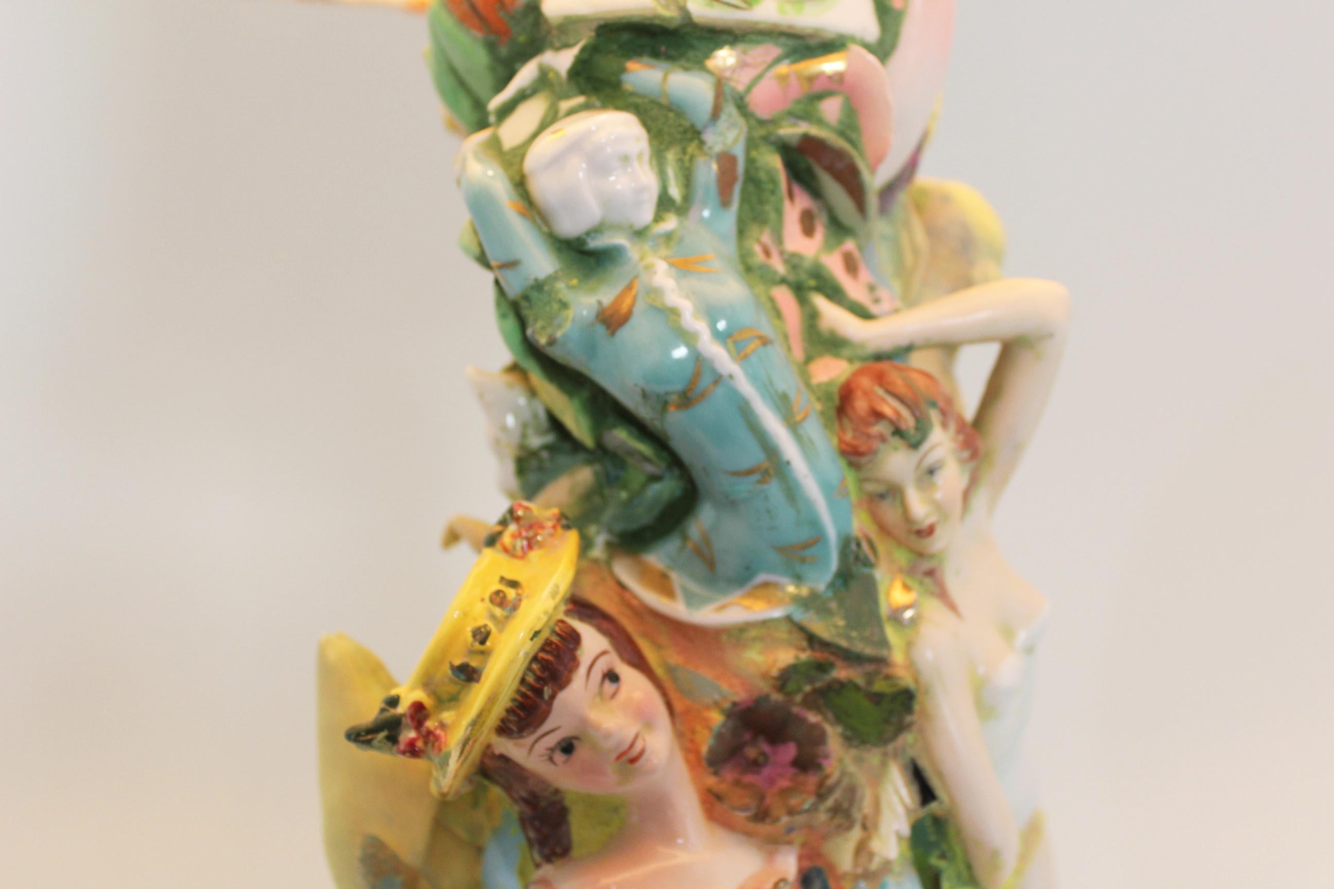This is a mixed media sculpture that is also a fully functioning lamp. The artist, Shannon Landis Hansen, works to incorporate ceramic figures, mosaic tiles, plates, cups and saucers into her pieces. This work reflects her fascination with what