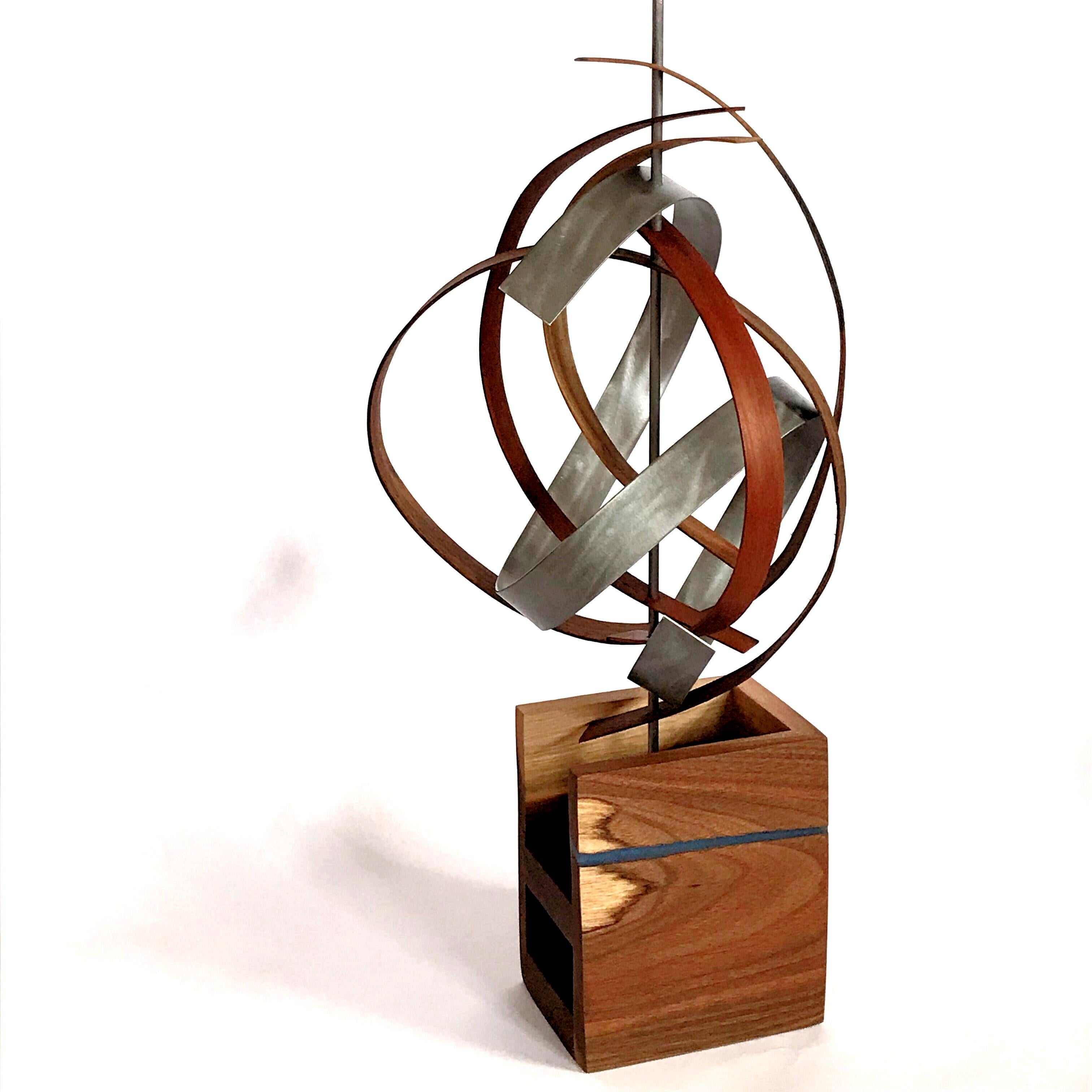 Title: G-Ribbon
Description: Aluminum slat with grind pattern and gun-metal finish looped like a ribbon through bent black walnut and cherry slats. Base consists of walnut slab, folded into three sides and accented with a blue epoxy streak.

Jeff