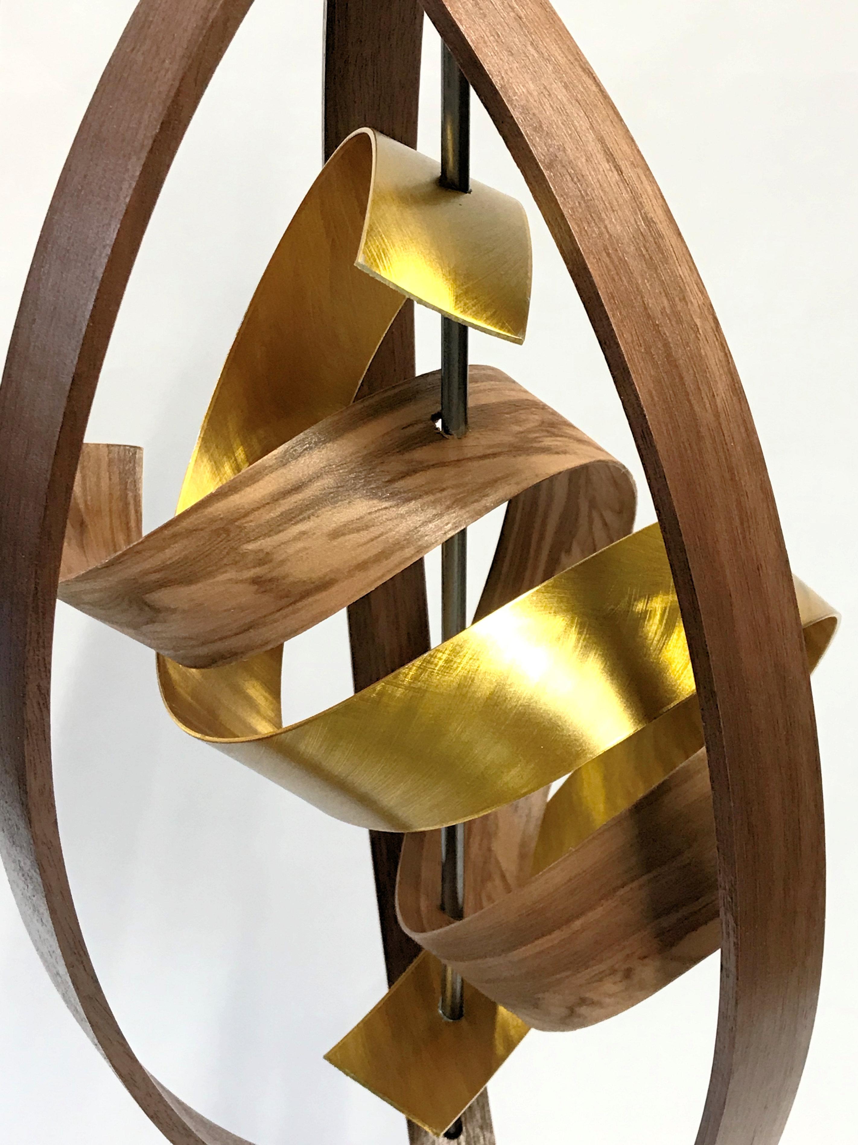 Description:  This sculpture top consist of formed and braided black walnut & red gum wood slats, accented with ground, gold-tinted aluminum slat and extends from a solid black walnut base.  Approx. 28”overall height, 8”x 9” spread. 
Title: