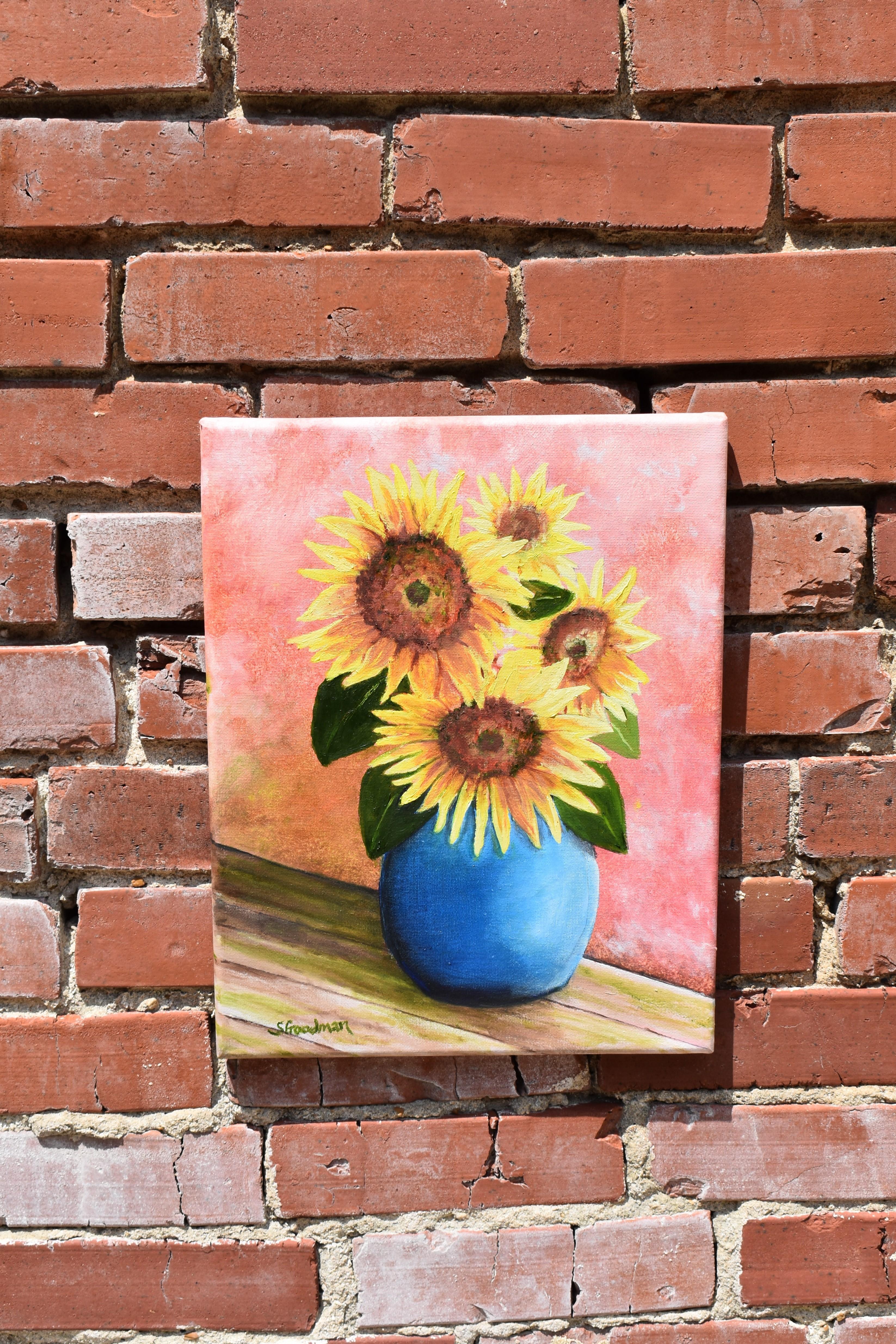 <p>Artist Comments<br>Artist Shela Goodman paints bright and colorful sunflowers in a blue vase. The impressionist still life captures the simplicity and beauty of nature. Shela paints vibrant yellow petals popping against the soft peach background.