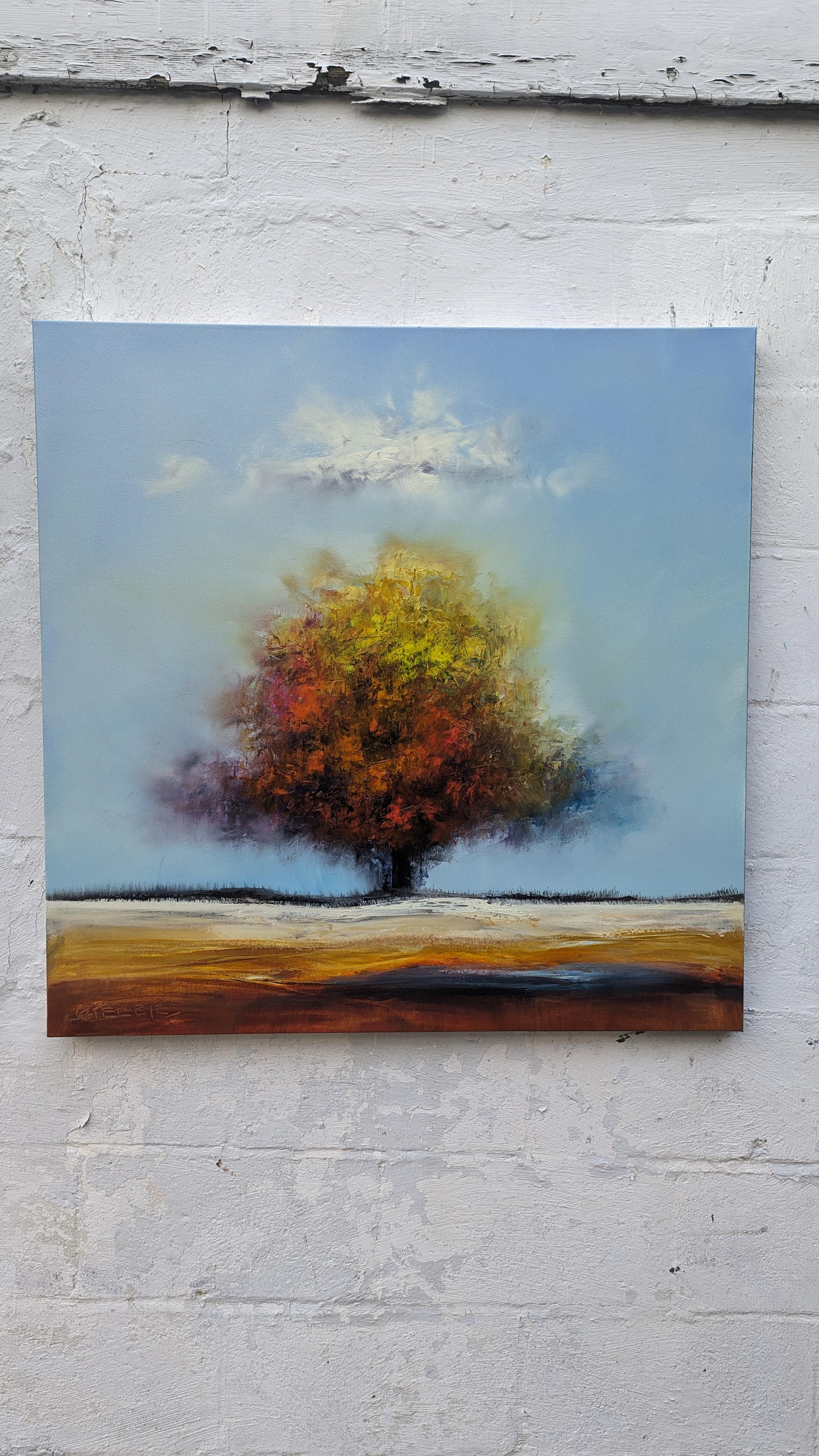 <p>Artist Comments<br>A lone tree stands in the middle of a vast meadow, with a single cloud hovering over it. Its leaves, painted in shades of yellow and red, subtly hint at the changing season. The vibrancy of the foliage stands out against the