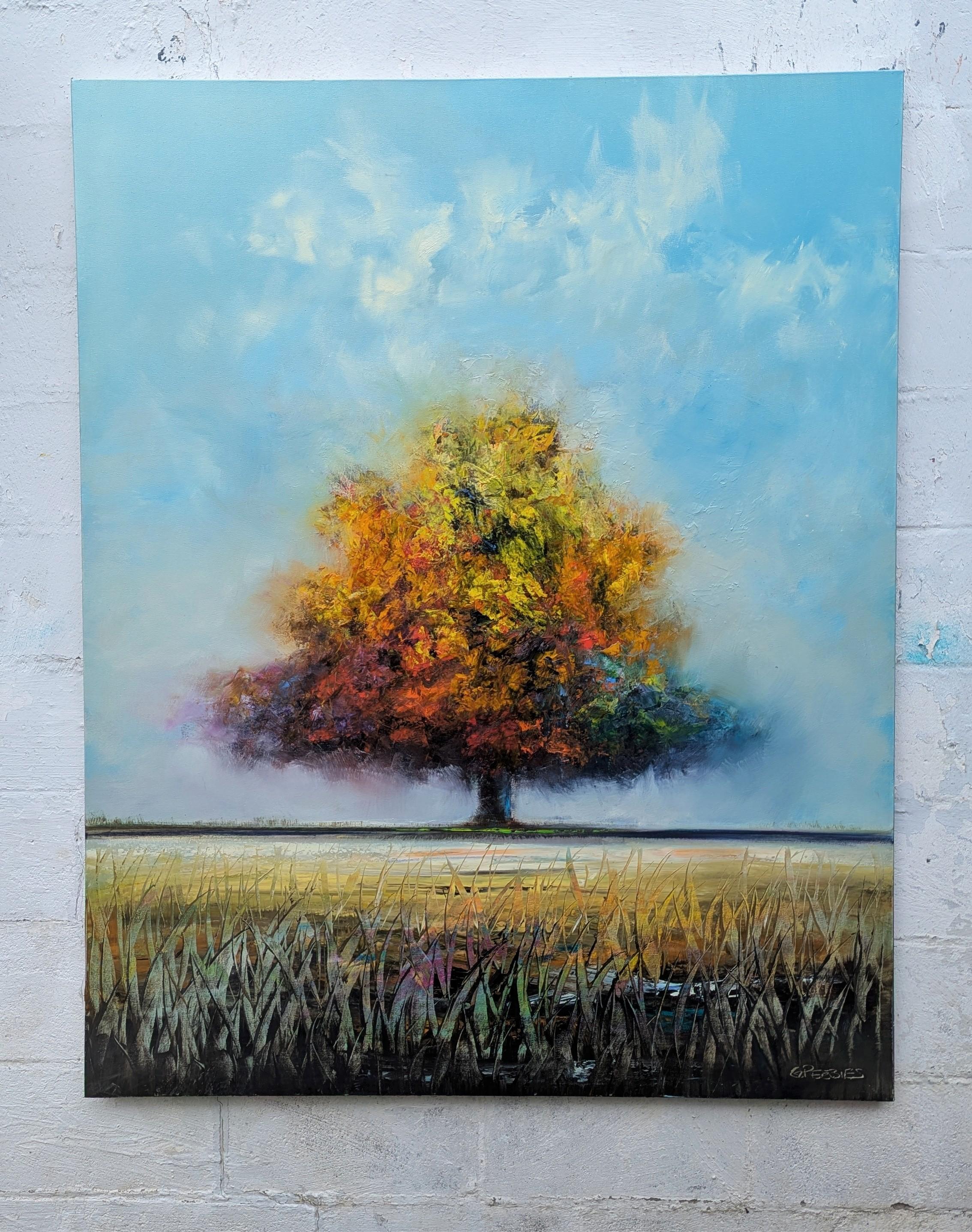 <p>Artist Comments<br />A colorful tree stands alone in an open field under a clear blue sky. The orange, yellow, and red leaves create a focal point against the soft, expansive background. Wispy grasses in the foreground add texture to the