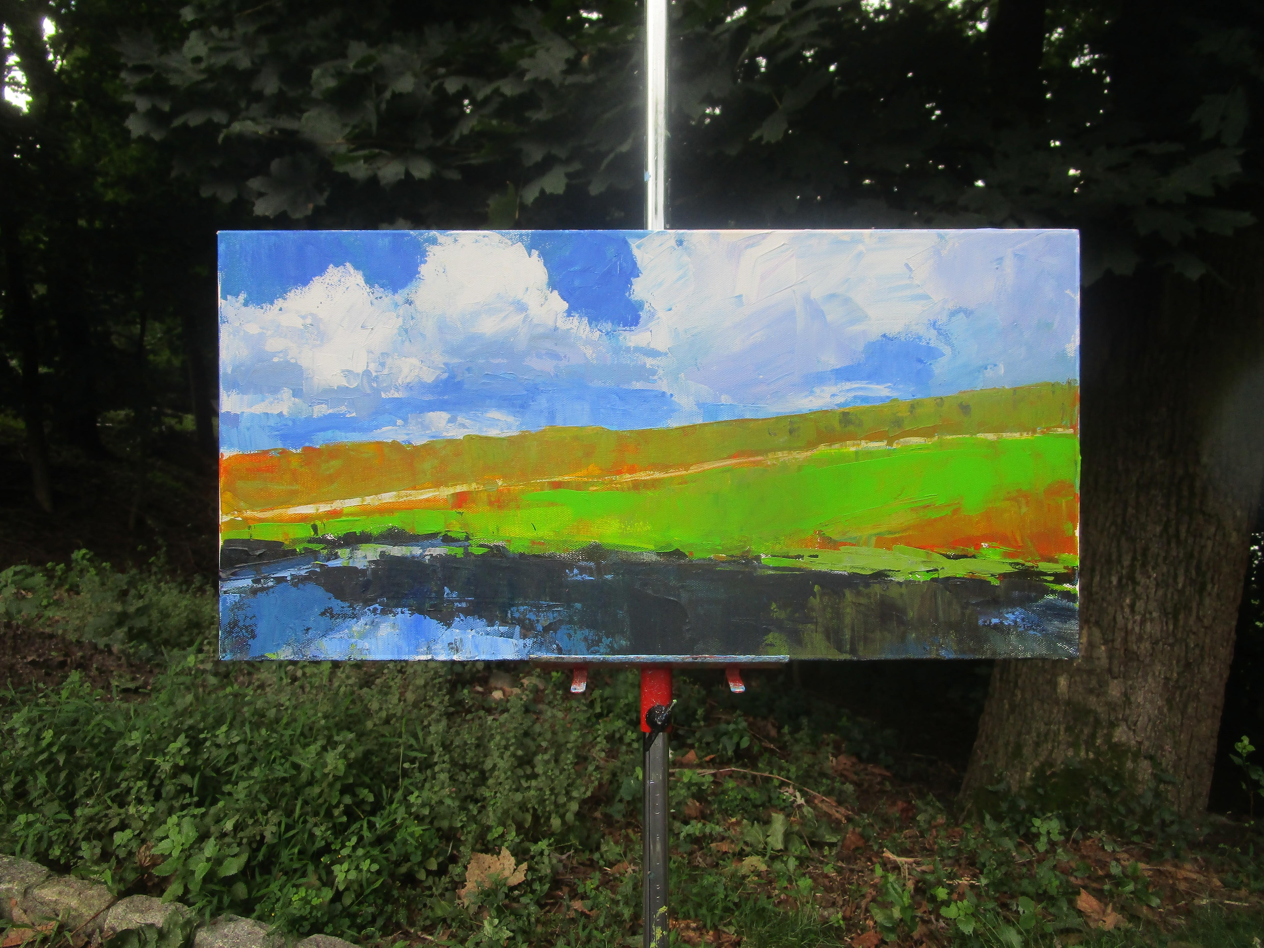<p>Commentaires de l'artiste<br />Des nuages brillants flottent dans le ciel bleu. Des teintes vertes et orange vives s'étalent sur les landes, tandis que des eaux réfléchissantes s'étendent le long du fond de l'eau. Cette scène ouverte capture la