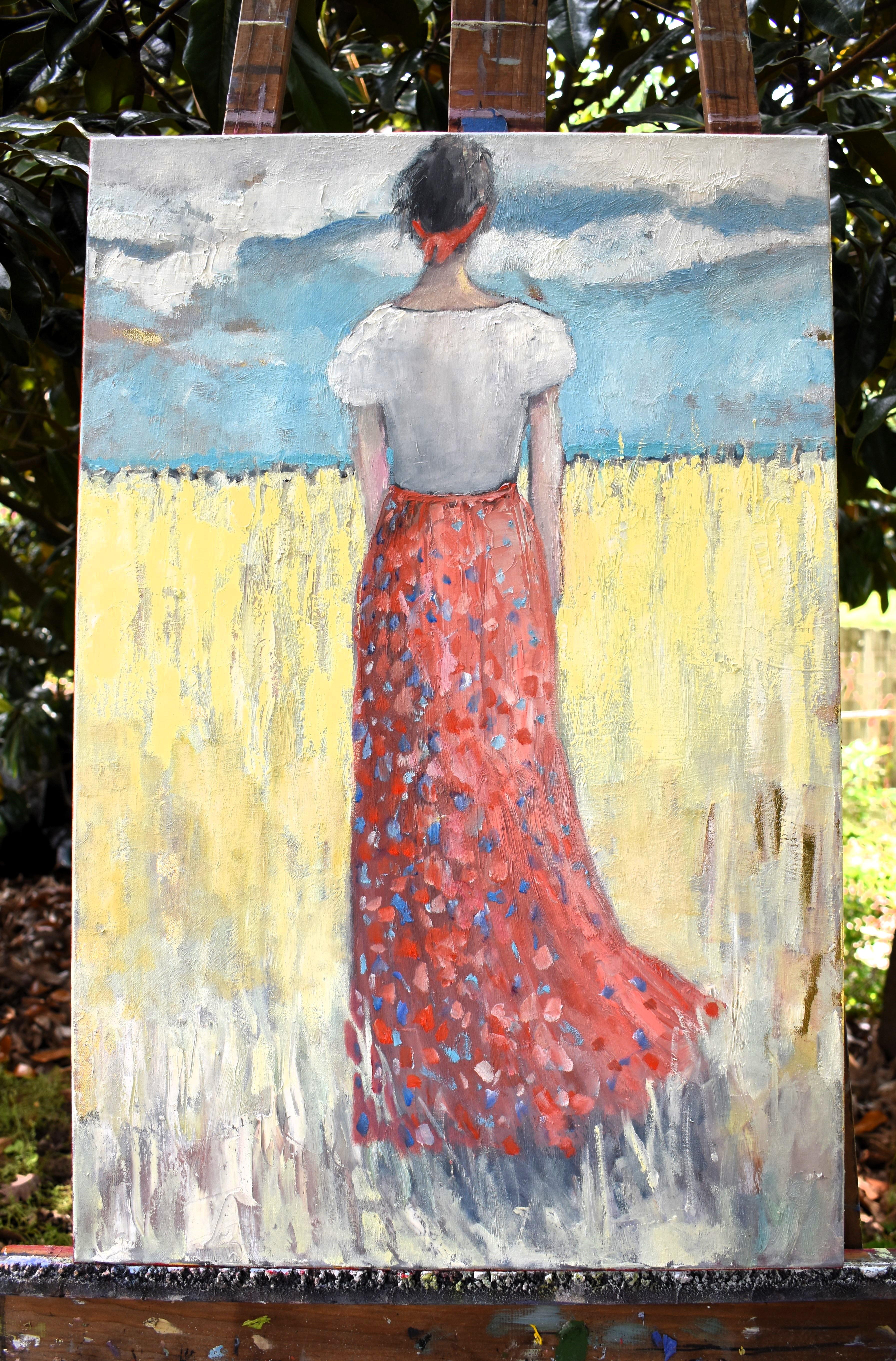 <p>Artist Comments<br>A woman stands in a sun-drenched field that stretches endlessly around her. Her vibrant red skirt contrasts beautifully with the golden grass, drawing the eye to the heart of the scene. She gazes up at a soft blue sky dotted