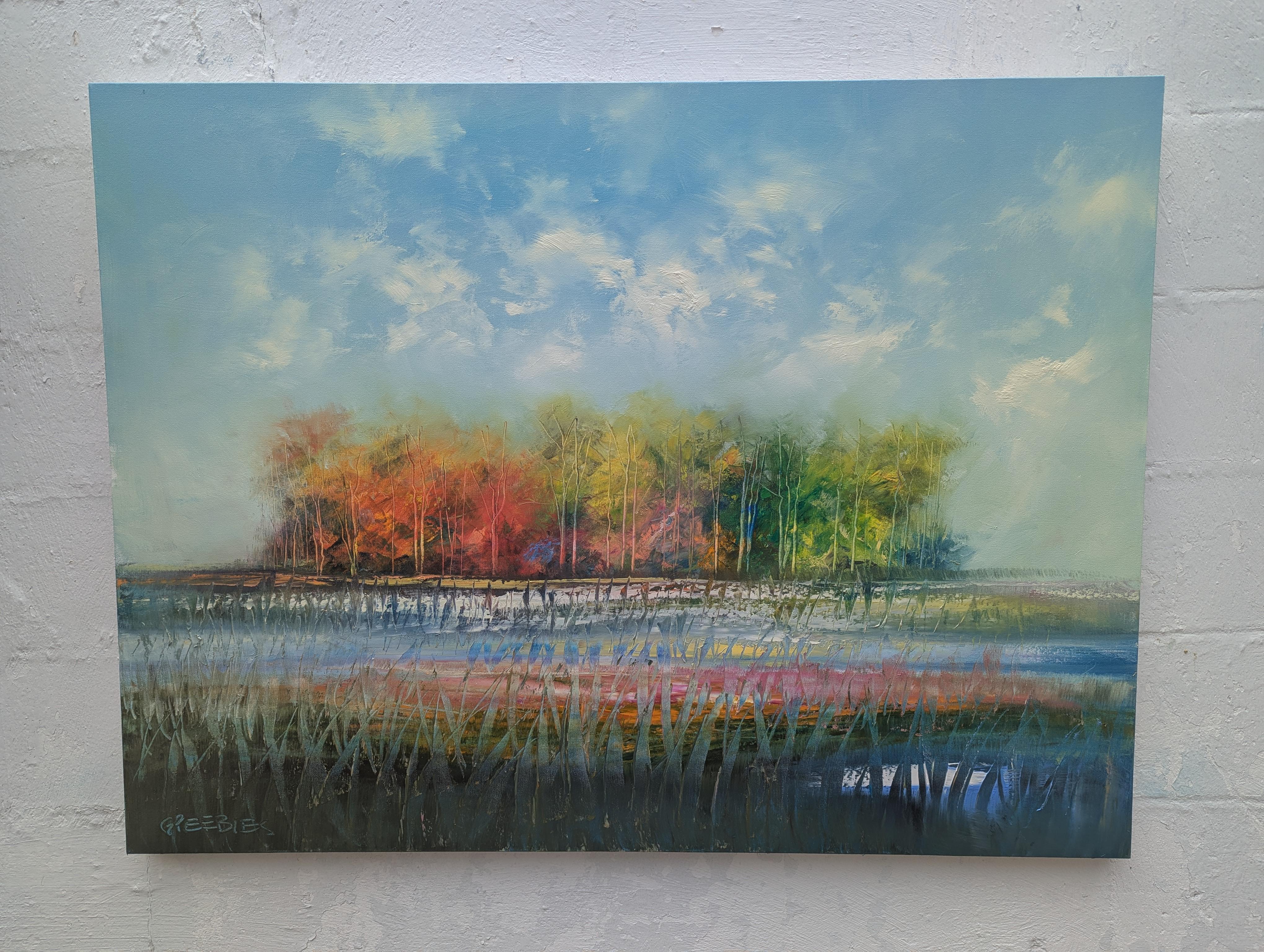 <p>Artist Comments<br>A stand of trees rises in the distance, its leaves presenting the colors of autumn. The thin clouds in the sky and wispy grass in the foreground create a sense of depth and scale. The reflective puddles enhance the vastness of