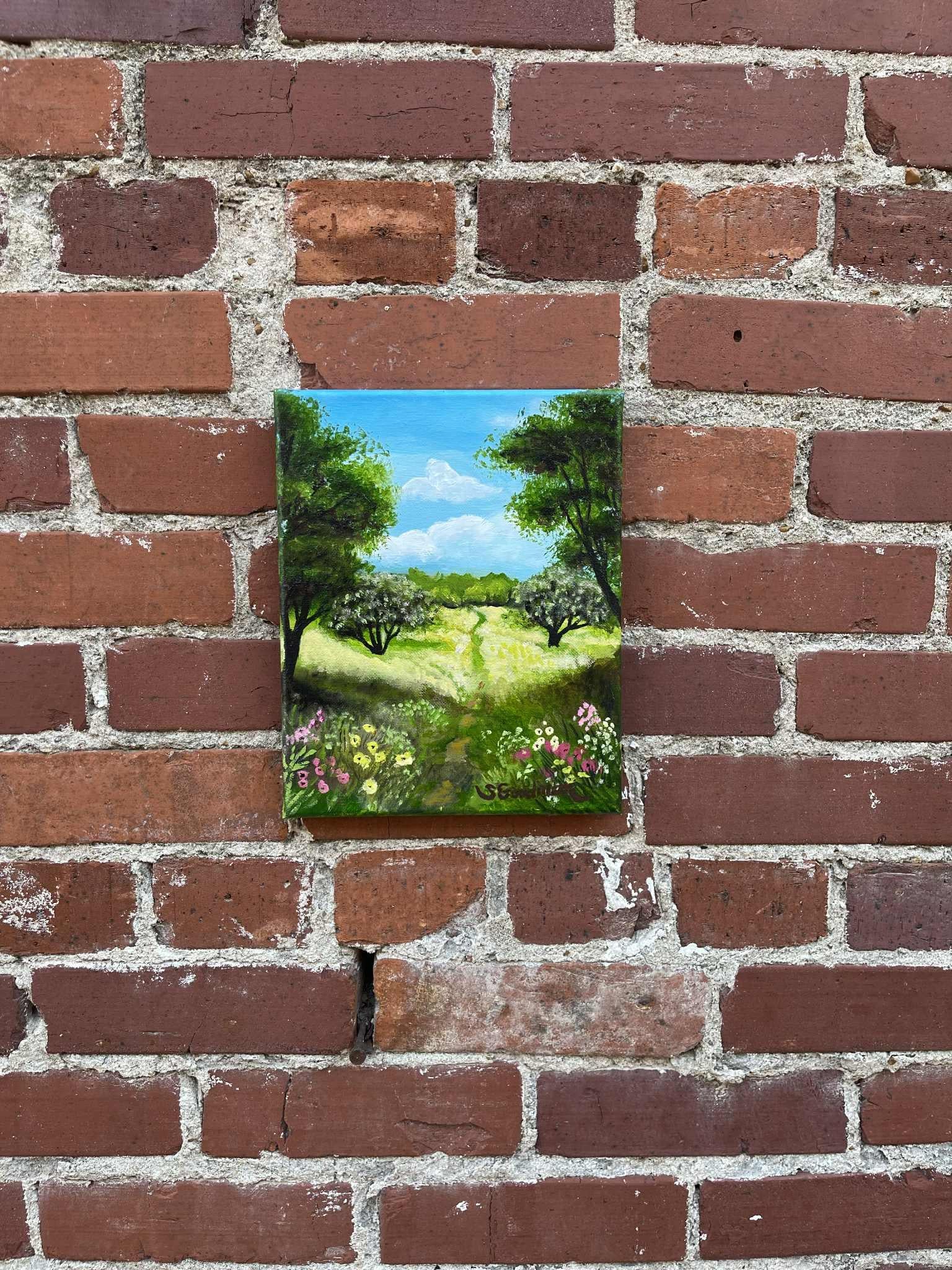 <p>Artist Comments<br>Fields of grass stretch untouched except for a path leading into distant woods. Flowers bloom in the shaded foreground, while bright sunlight illuminates just beyond. Overhead, soft clouds drift lazily across a clear blue