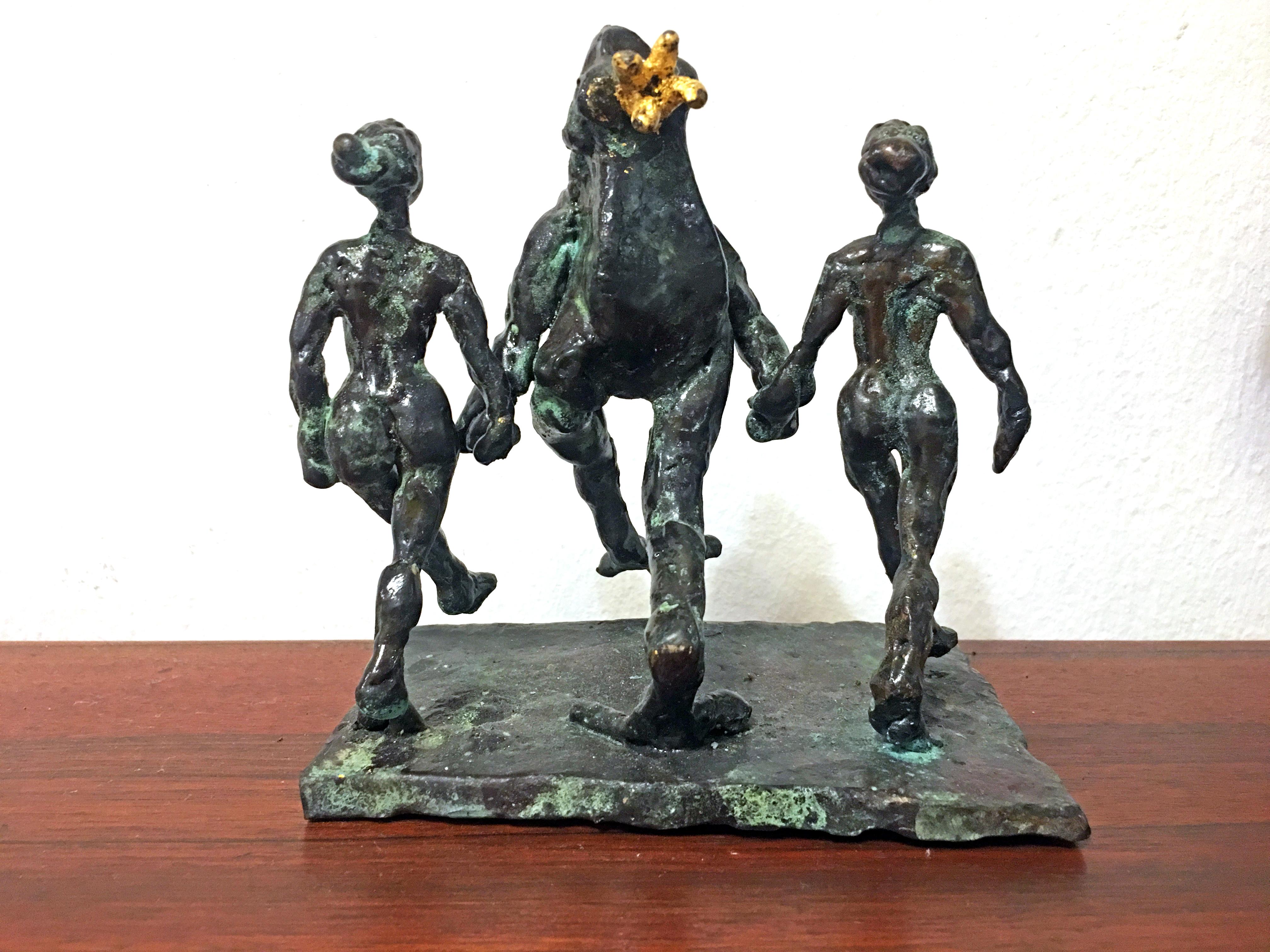 Sculpture en bronze de l'artiste danoise Helle Crawford représentant une grenouille accompagnée de deux femmes qui dansent.
