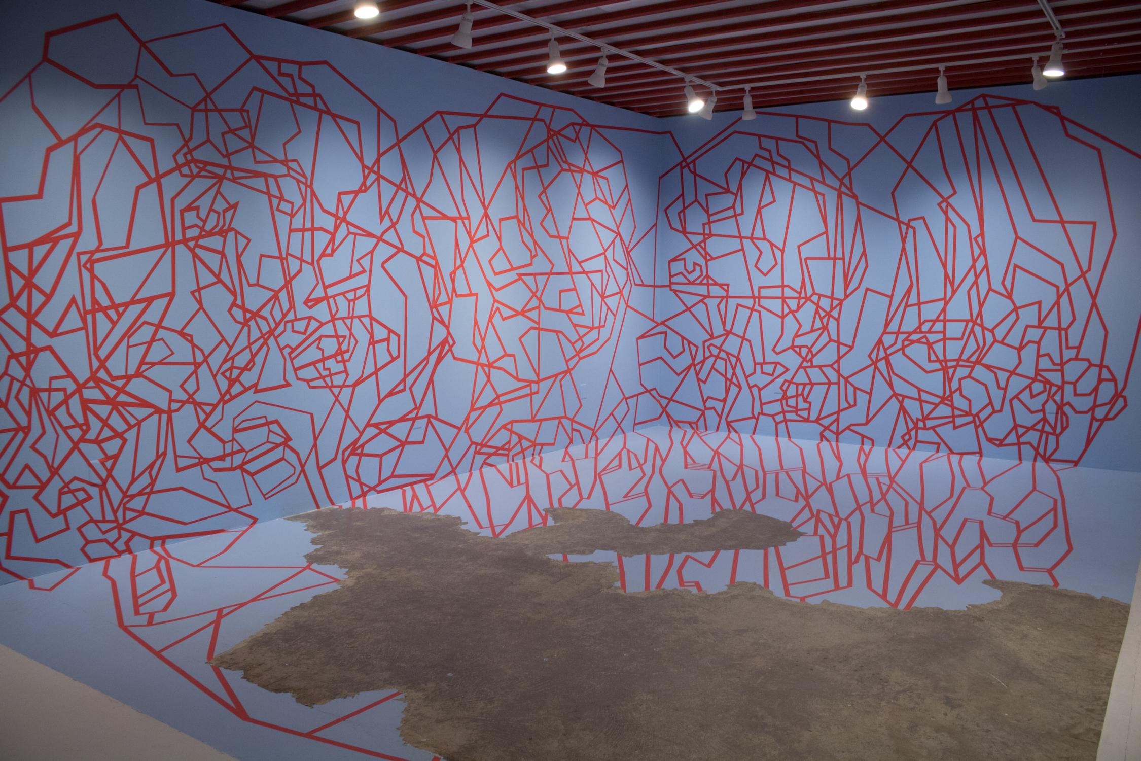 "Cutting Edge" ist eine Installation von Dustin Hedrick, die aus Farbe und Klebeband besteht. Das rote Klebeband schafft ein geometrisches, abstraktes Porträt auf den blau gestrichenen Wänden. Dabei wird der negative Raum der blauen Wand, der durch