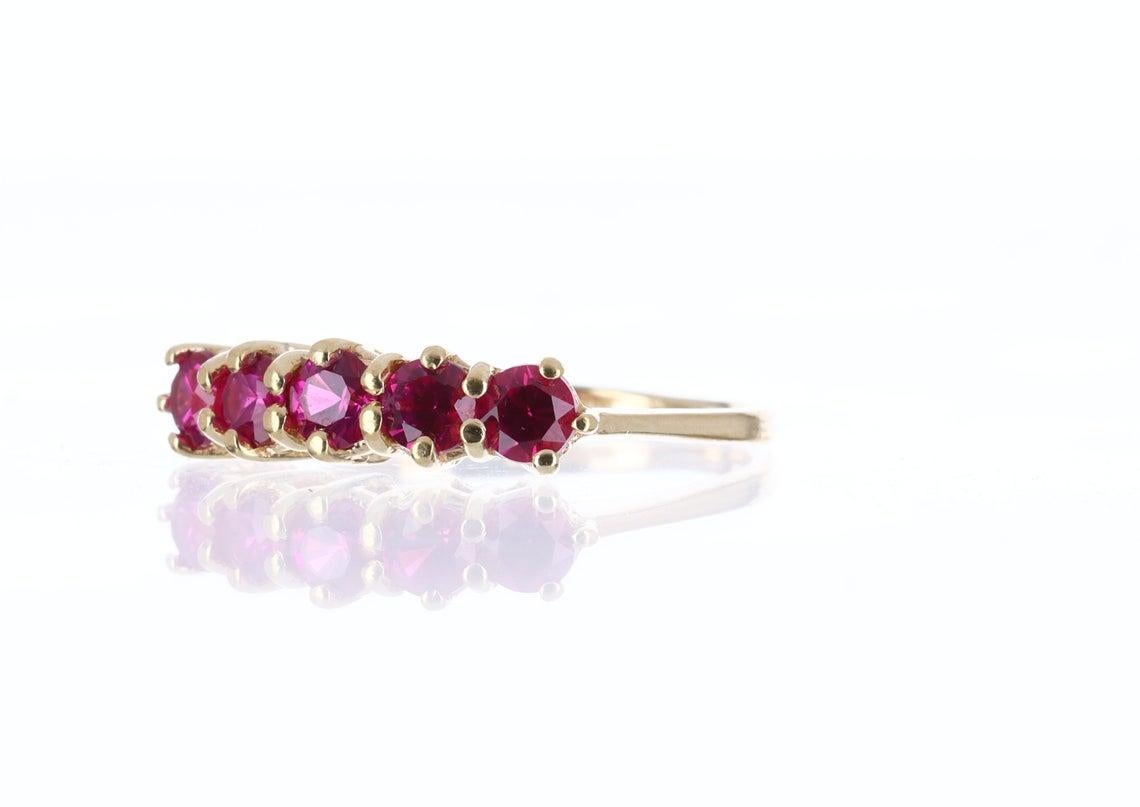 Delicately displayed is an ultra chic, rubellite ring band. Dexterously handcrafted in gleaming 14k yellow gold, this ring features a row of matching, genuine AAA+ quality rubellite's. Five natural rubellite's are beautifully saturated and have an
