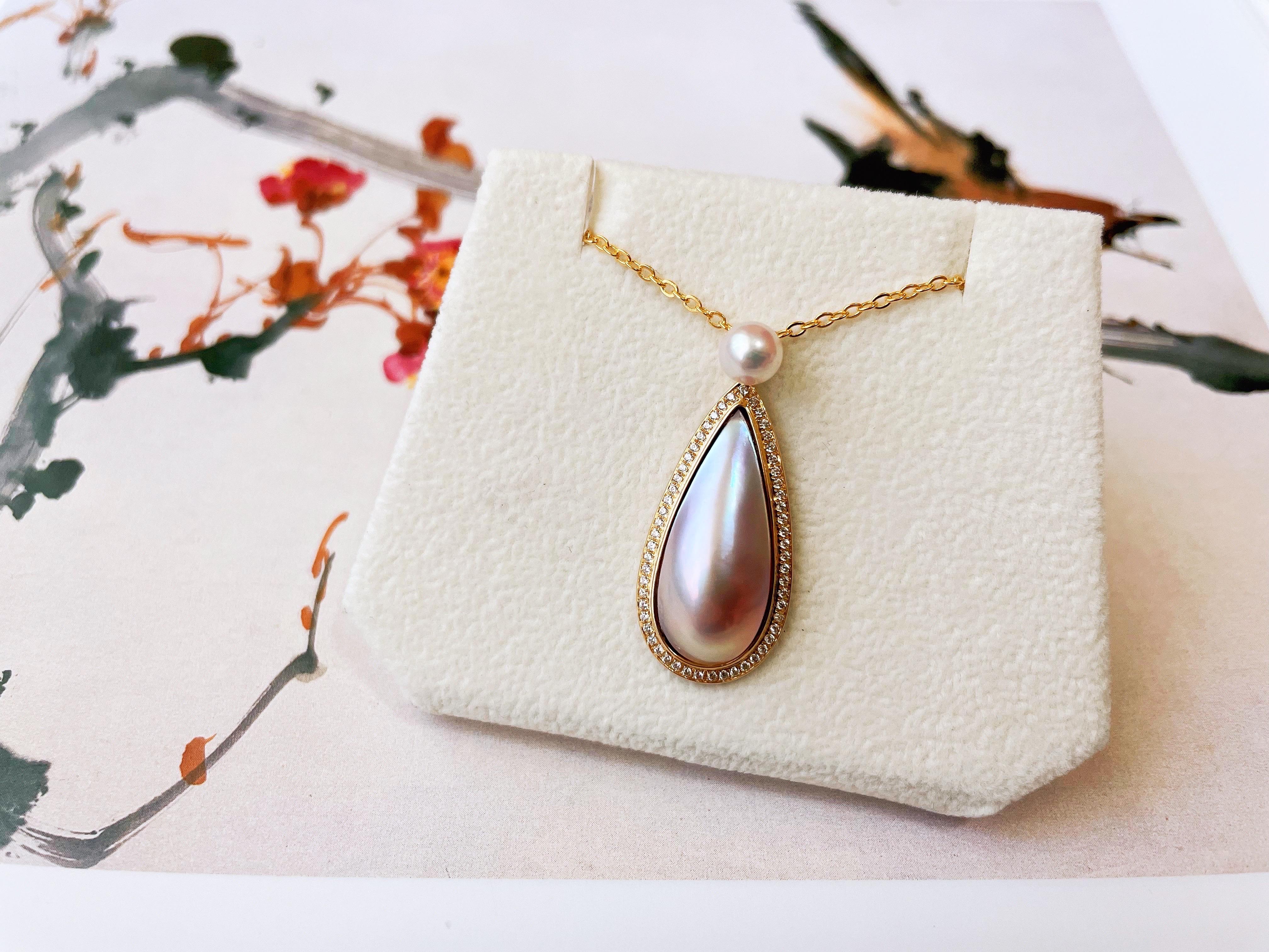 Experience the beauty of Japanese craftsmanship with this exquisite mabe pearl pendant from Amami island. The iridescent color of the pearl creates a stunning display of hues, while the 18K gold setting and brilliant diamonds add a touch of
