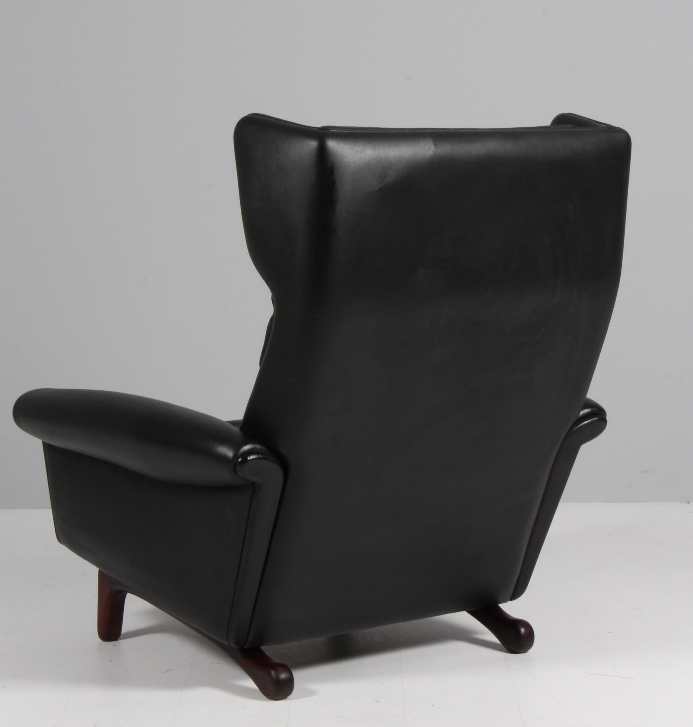 Aage Christiansen lounge chair in original black leather.

Legs of stained wood.

Made by Erhardsen & Andersen / Eran møbler.