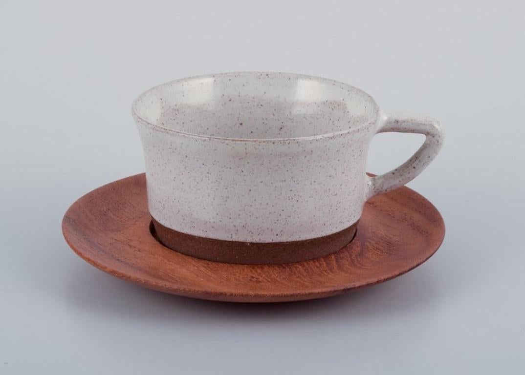 Aage Rasmus Selsbo (1926-1996), Danish ceramic artist.
A unique three-piece coffee service in stoneware with wooden saucers. 
Sleek Scandinavian design.
Approximately 1970.
Signed.
In perfect condition. Appears unused.
Cup: Diameter 8.7 cm. without