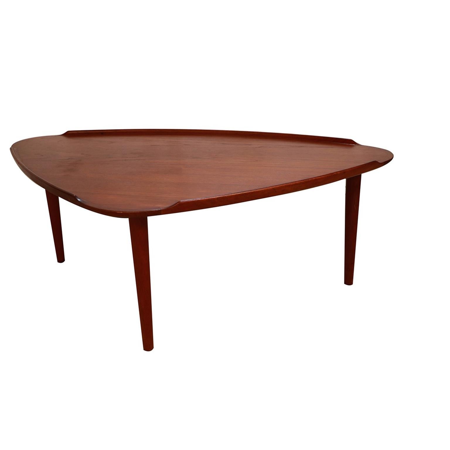 Spectacular 1960s Danish modern teak tripod triangular coffee table designed by Aakjaer Jorgensen for Mobelintarsia, Denmark, circa early 1960s. Features a triangular “guitar pick” shaped top in beautifully grained teak with carved lip edges