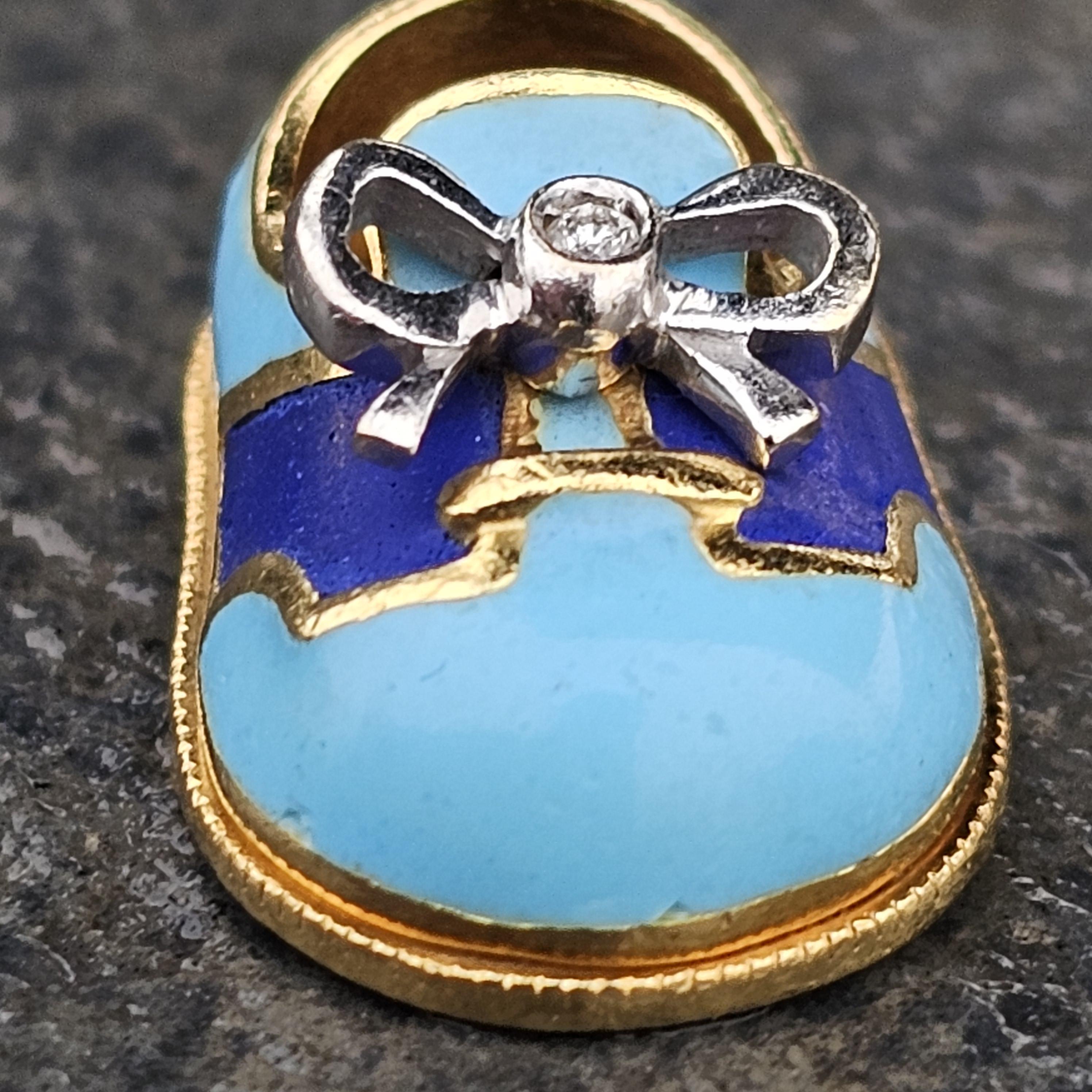 This exquisite Aaron Basha charm is crafted from 18k yellow and white gold, featuring a delightful baby shoe design. The charm is adorned with a white diamond at the center of a delicate bow, adding a touch of sparkle and elegance. Perfect for a