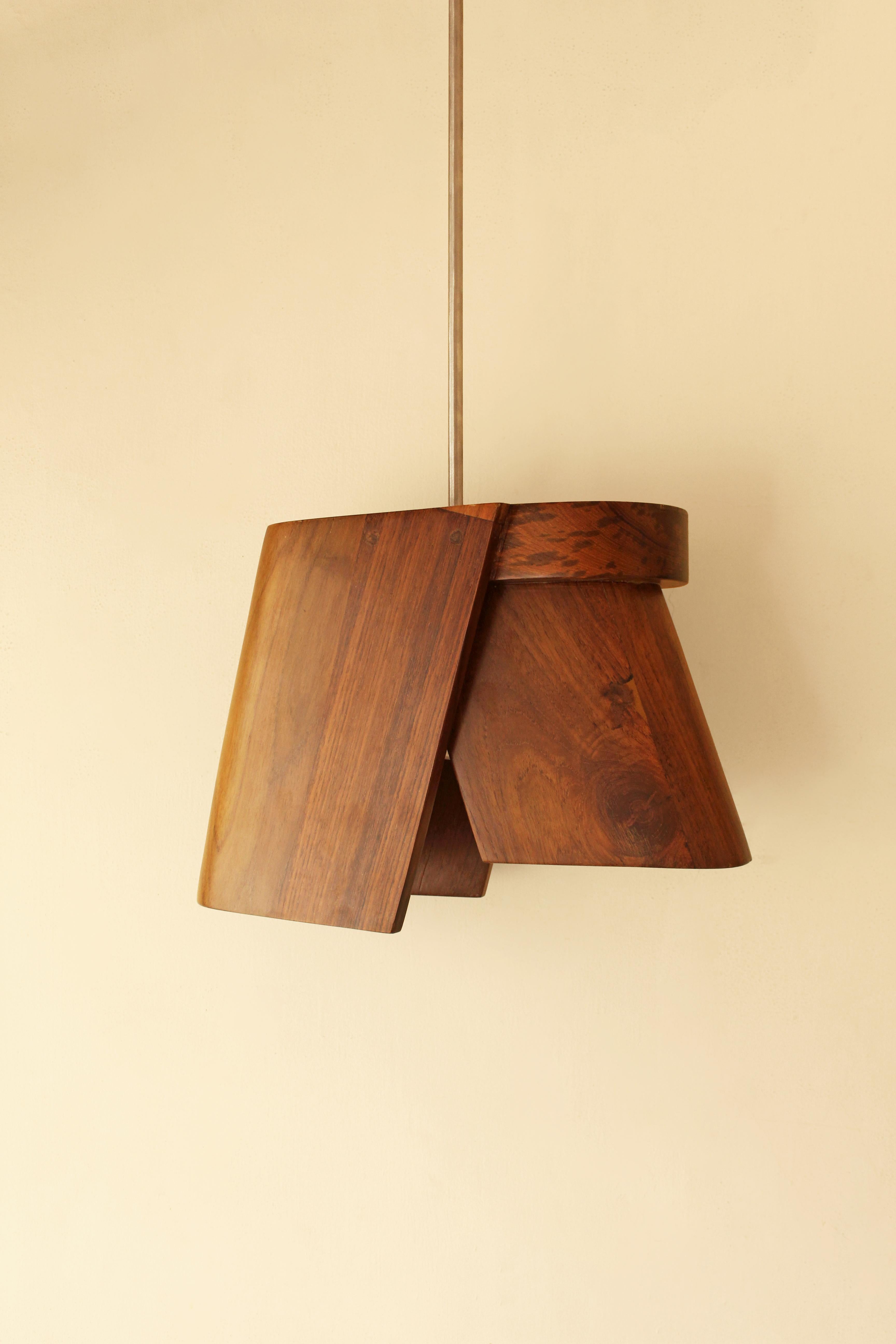 Aavaran Pendant Light by Studio Indigene
Dimensions: D 40.64 x W 14 x H 27.94 cm
Materials: Reclaimed Teak Wood & Stainless Steel (suspension rod). 
Colors Brown, Natural Wooden Finish.

Hand-carved out of solid reclaimed teak wood, Aavaran throws a
